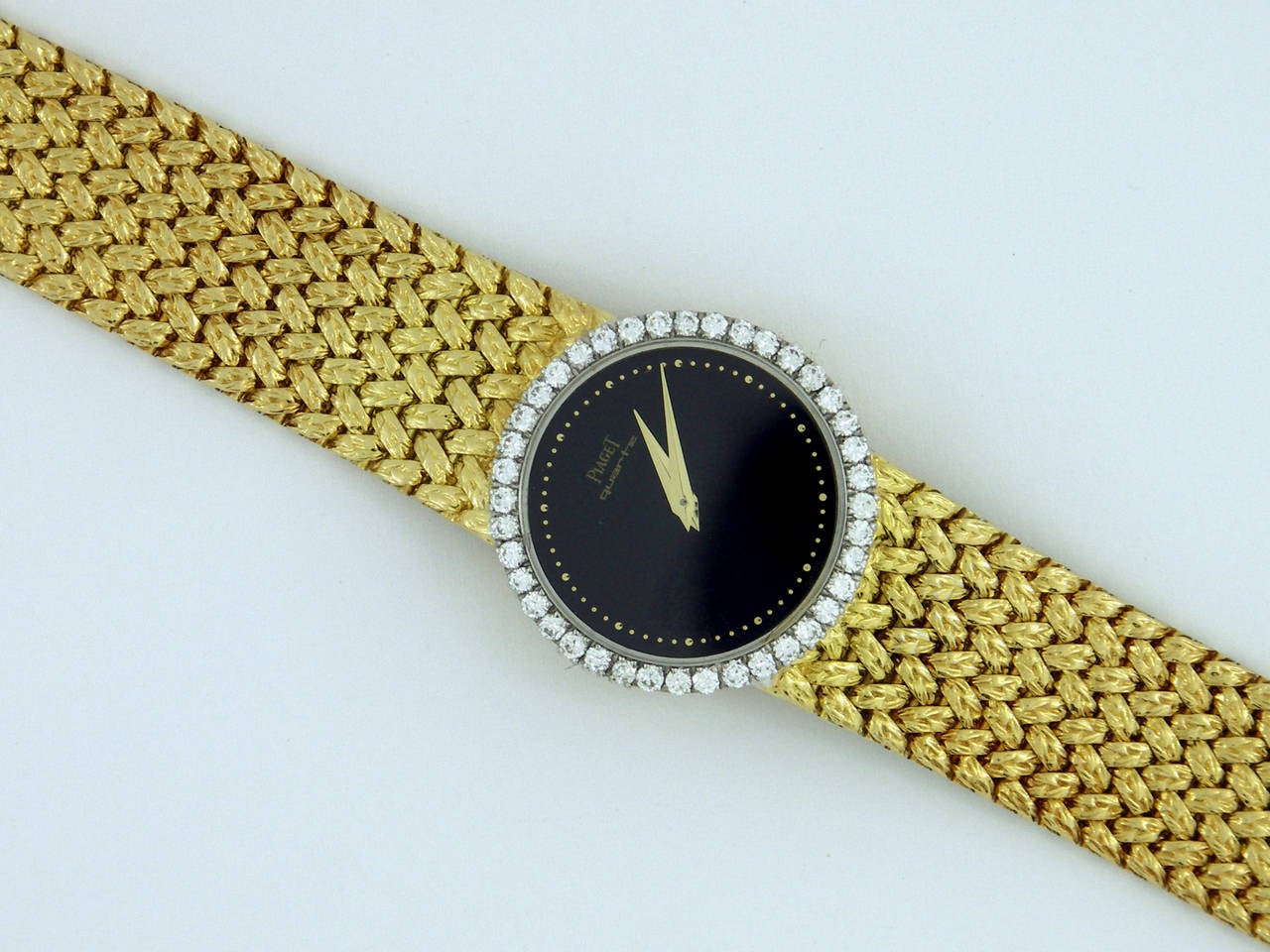 A striking 18K yellow gold Piaget lady's watch. This fabulous timepiece features an onyx dial with gold lettering and markers. Surrounding the dial is a 25mm bezel set with a total of approximately 1 ct of round brilliant-cut diamonds. Diamonds are