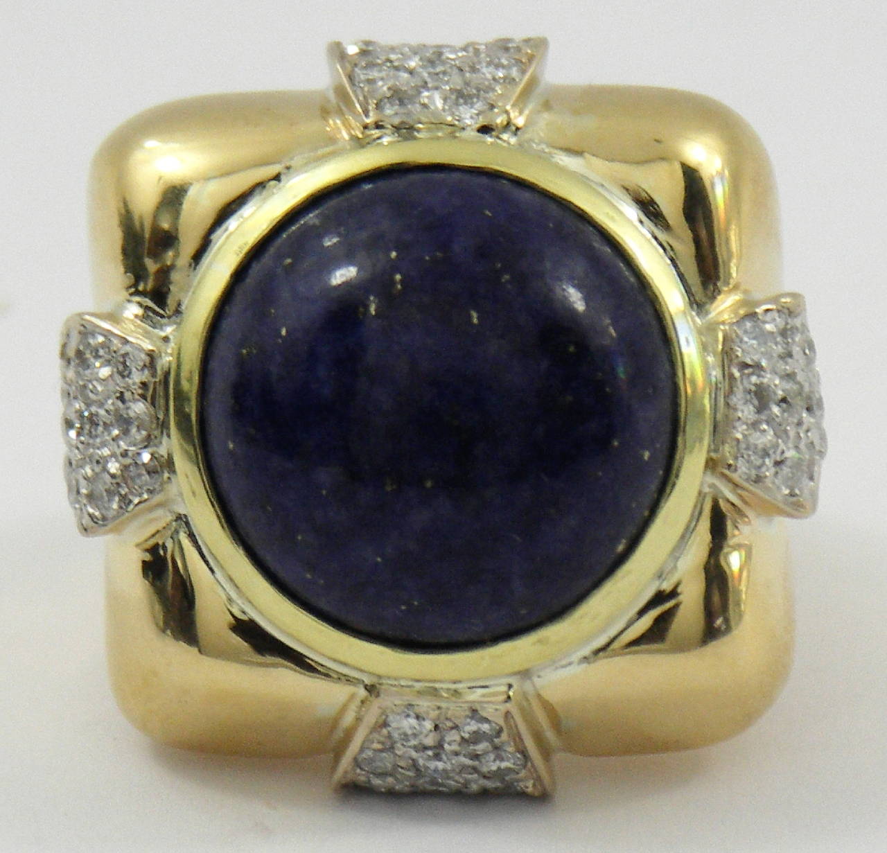 An 18K yellow gold ring signed A. Clunn, and set with 50 diamonds, weighing 2ct total approximate weight. The center is set with a round, cabochon cut Lapis Lazuli, measuring 17mm. 
Size 6 1/2