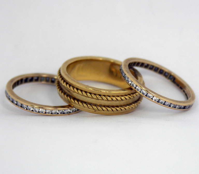 A set of three yellow gold bands by Tiffany & Co. Two of the bands are channel set with E/F color and VVS2/VS1 clarity diamonds for a total approximate weight of one carat. The center band is comprised of a high polished background, upon which are