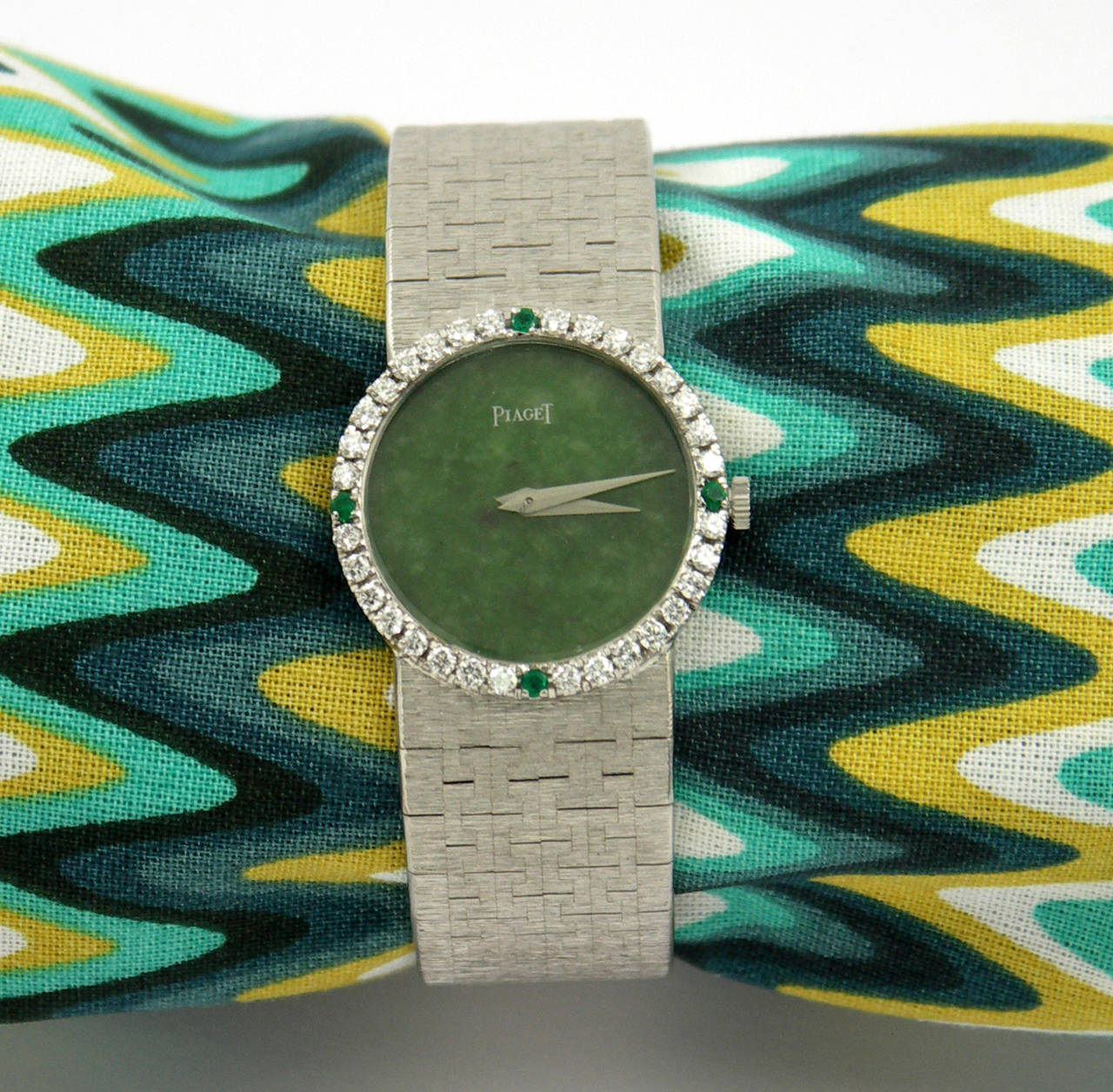 This much sought after 18K white gold, round jade dial, Piaget, is set with a
diamond bezel with four brilliant emeralds in the 12:00, 3:00, 6:00 and 9:00
positions. Total approximate weight 1.00CT. Overall length is 6 1/4 inches. Watch head
