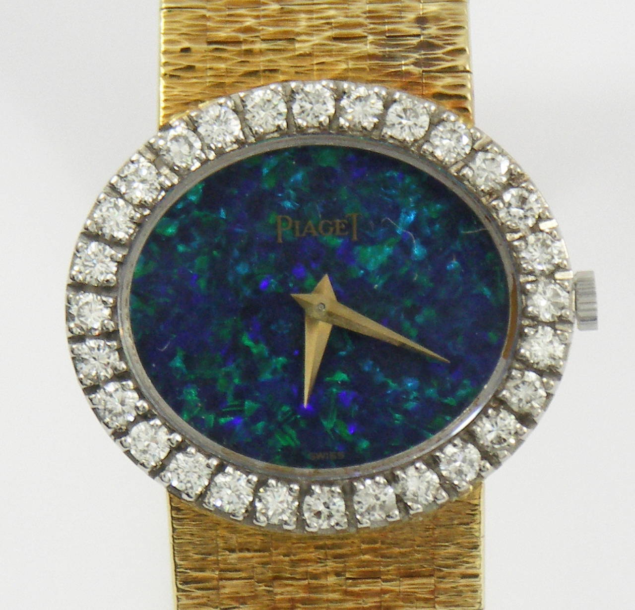 One ladies 18K yellow gold Piaget wrist watch. This elegant timepiece features a black opal dial, rich with green and blue 