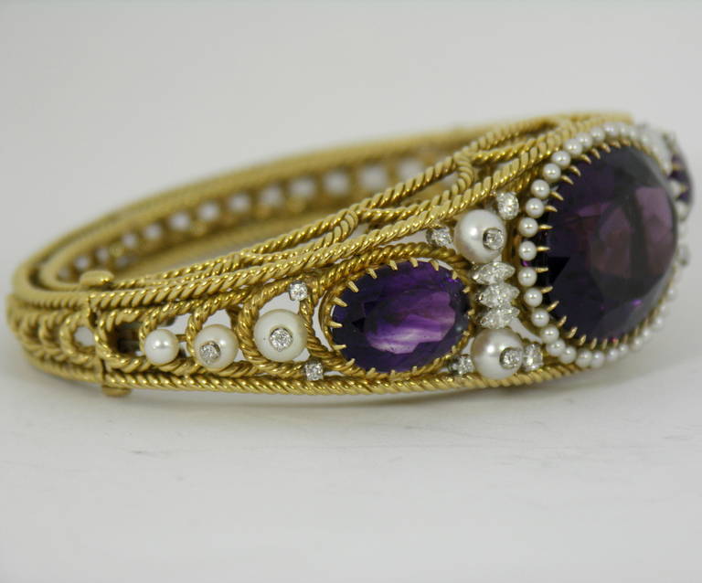 A beautifully hand made bracelet, crafted from drawn and twisted wire. Set into its frame, are three oval faceted amethysts weighing 60ct total approximate weight. The center amethyst is surrounded by seed pearls, and the bracelet accented by 10