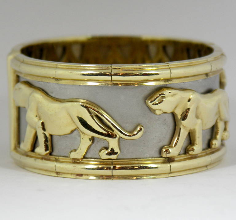 A beautiful cuff bracelet, measuring 1 1/8 inches wide. With a frame constructed of yellow gold, and a sheet of white gold used as a background, there are 4 big cat embellishments. This artistic panther bracelet will fit up to a 6 3/4 inch wrist