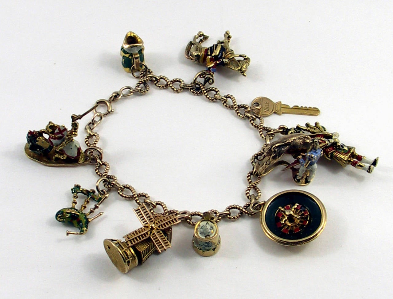 An unusual charm bracelet in 9K gold. This fun mid century piece features English hallmarks but highlights other European countries as well. The Dutch windmill, Monte Carlo roulette wheel, beer stein, and Saint George charms all have motion. This