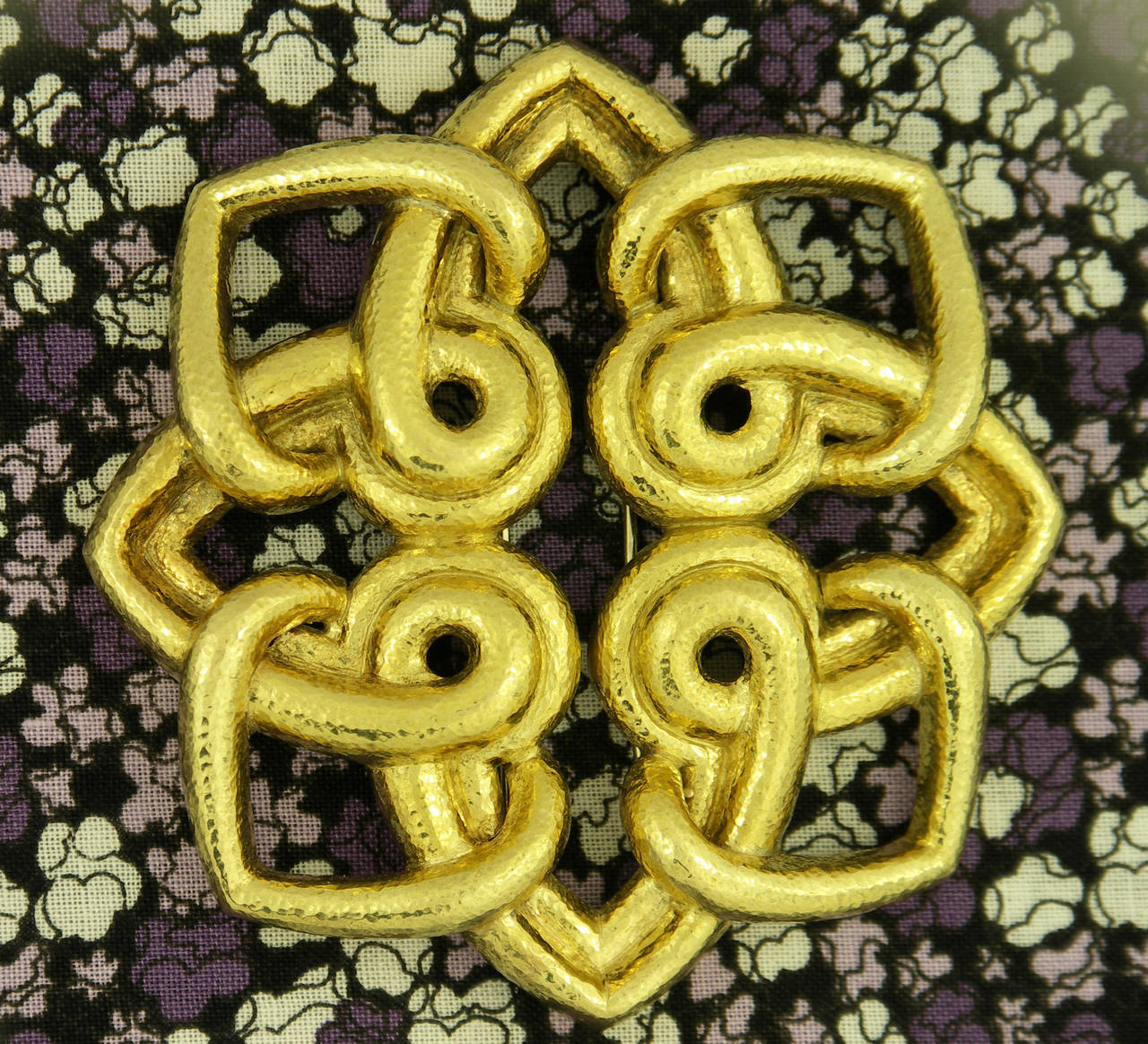 A Brooch by David Webb in 18K yellow gold, featuring an interlocking design, not unlike a snowflake. With eight points, this brooch measure three inches in diameter. The geometric design is accentuated by the beautiful hammered finish.
