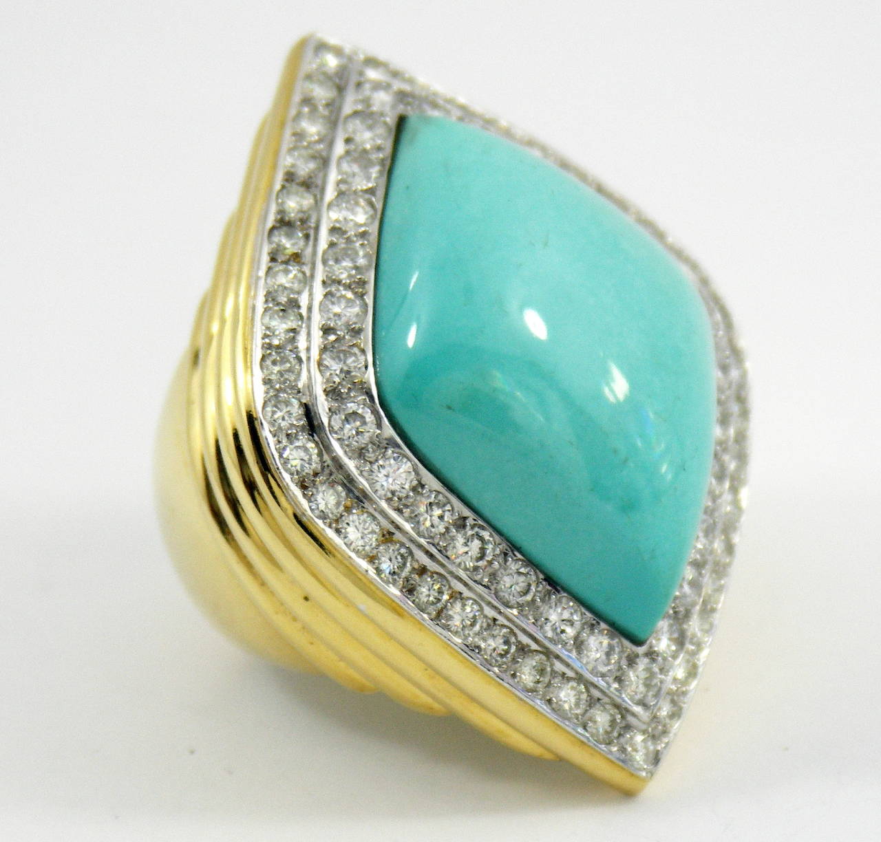 One ladies 18K gold ring, with shoulders beautifully tiered, leading up to a turquoise and diamond top. Beautifully pave' set with 68 round brilliant cut diamonds, totaling approximately 5ct, they surround the navette shaped, cabochon turquoise,