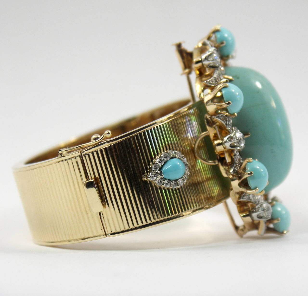 A 14K yellow gold corrugated design bangle bracelet, set with two pear-shaped turquoise and 26 round brilliant cut diamonds. This bracelet is embellished with a Victorian era brooch. Constructed with an 18K yellow gold frame it features a platinum
