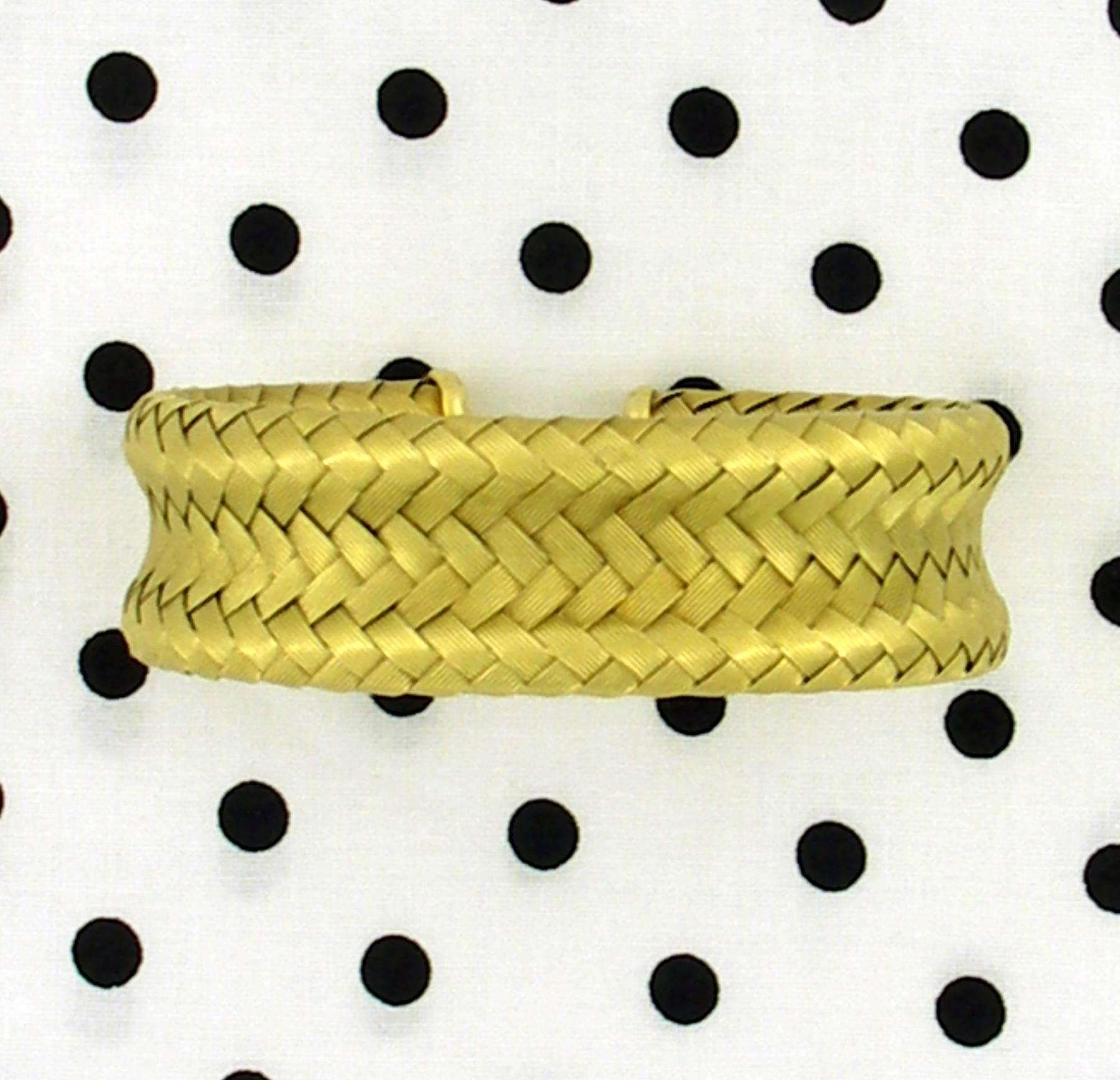 An 18K yellow gold cuff, with a basket weave design, measuring 7/8 of an inch wide with an inside circumference of 7 inches. Bracelet's hallmark denotes manufacture in Vicenza, Italy.