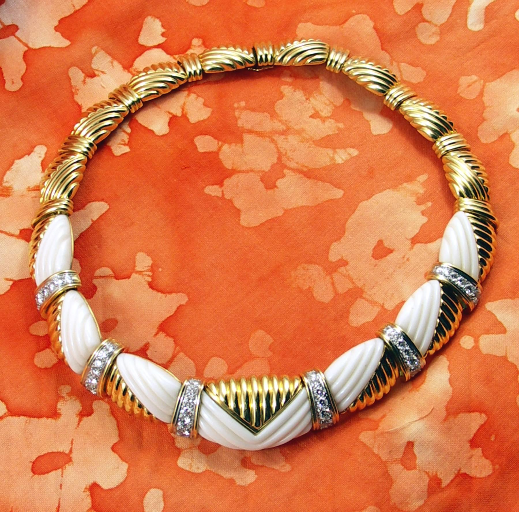 A ladies necklace in 18K yellow gold by Charles Turi, tapering in width from 1/2 inch to 3/4 of an inch. The necklace is embellished with 7 sections of fluted white coral, and is set with assorted round diamonds weighing 4ct total approximate weight