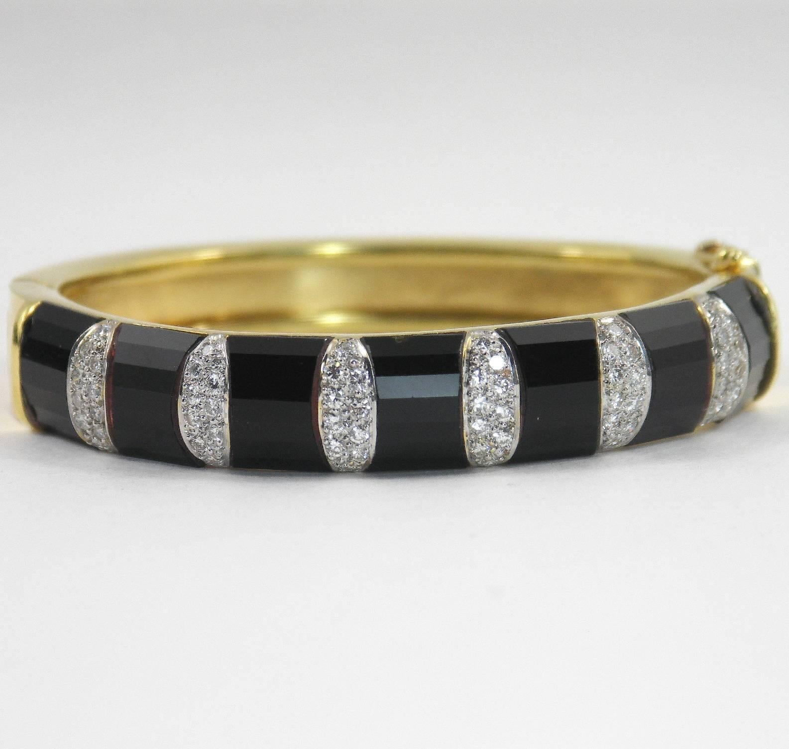 An 18K yellow gold bracelet set with seven onyx slabs, and six pave' diamond sections. Measuring 1/2 an inch wide, the diamonds weigh 1.25ct total approximate weight, and are of overall F/G color, and VS1 clarity. 
Inside circumference is 6 1/2