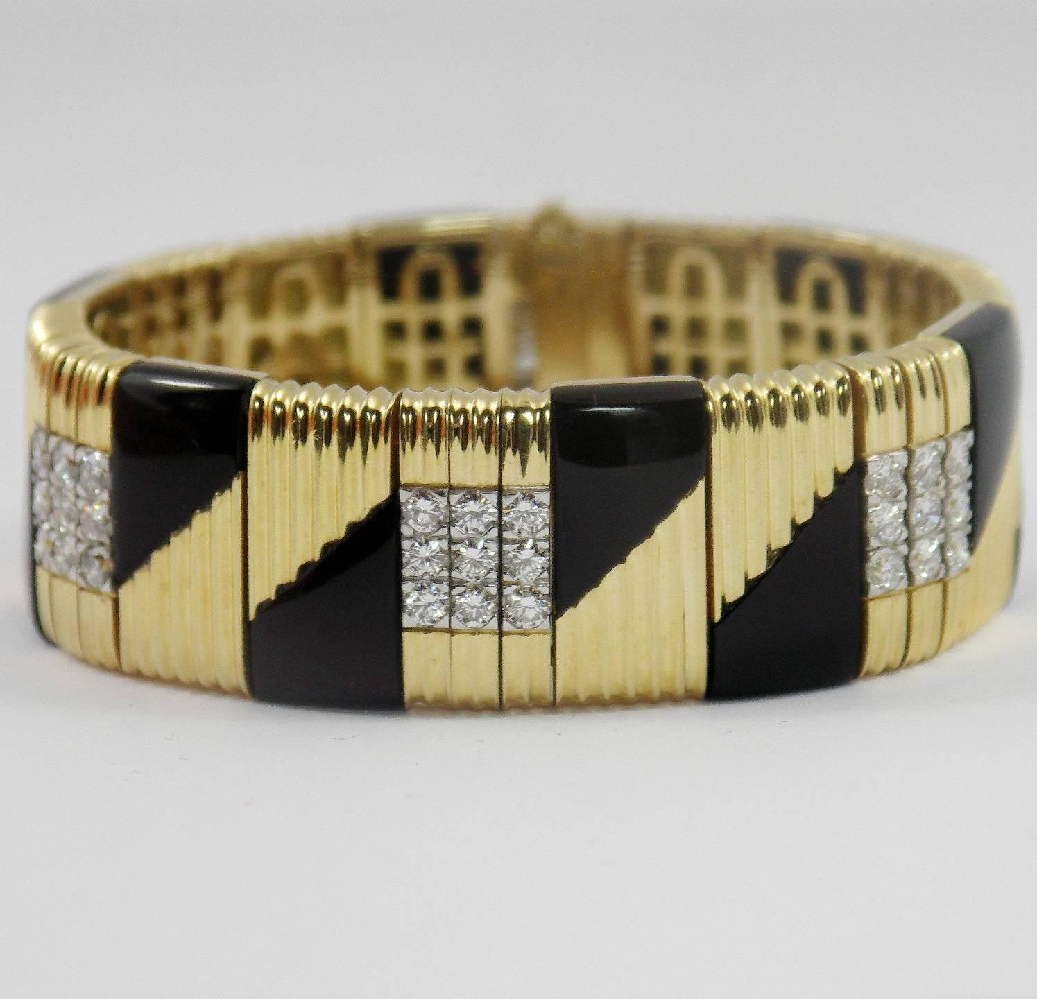 An 18k yellow gold bracelet comprised of six panels, each centering on 9 round brilliant cut diamonds with mirror imaged onyx, against a background of ribbed gold. The total approximate weight of the 54 diamonds is 1ct, and diamonds are of overall G