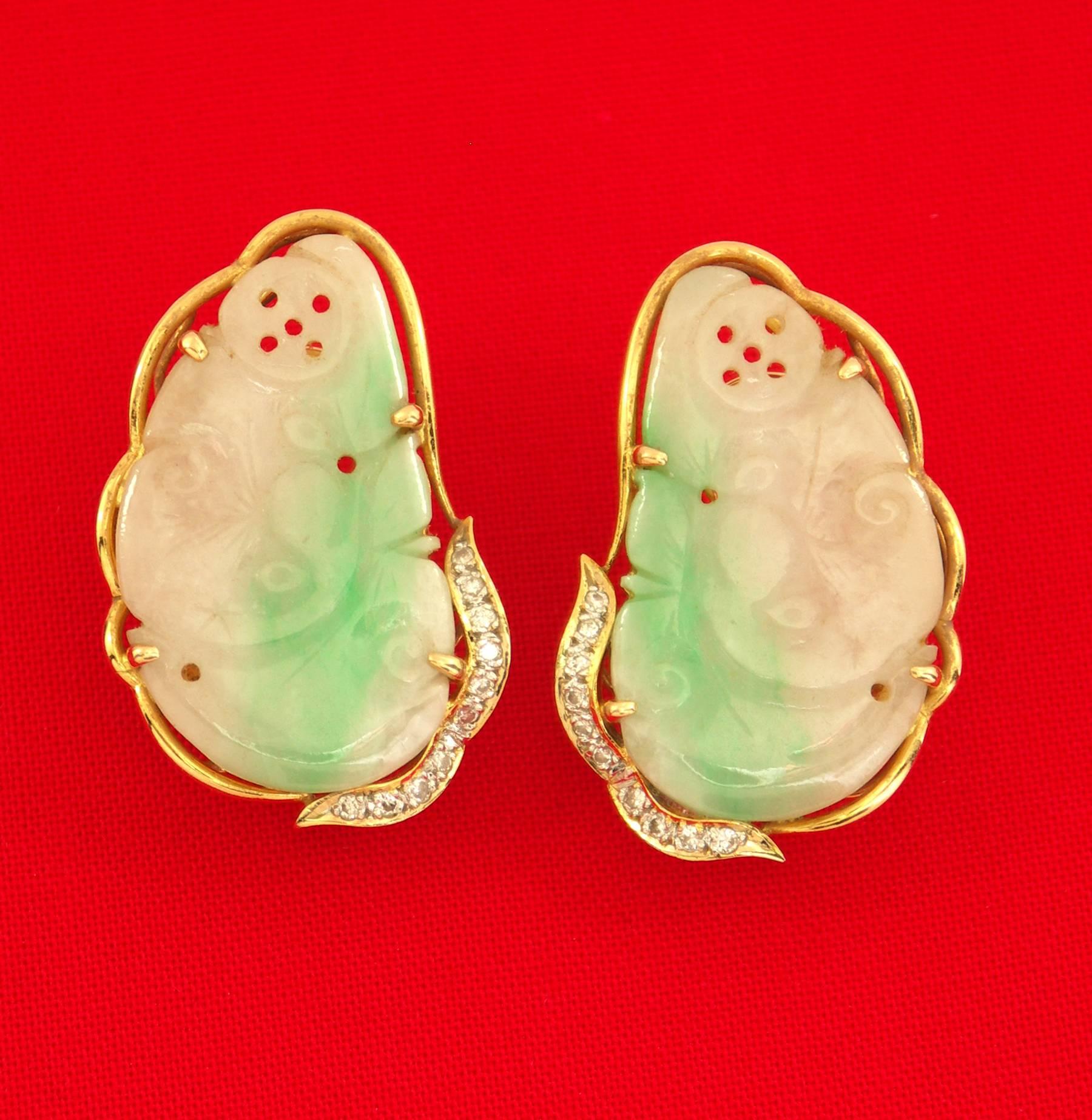 A pair of 18K yellow gold earrings, each set with a piece of carved jade measuring 1 1/4 inches long, and 5/8 of an inch wide. Each earring is also set with 10 single cut diamonds with a combined overall weight of approximately 0.25ct.