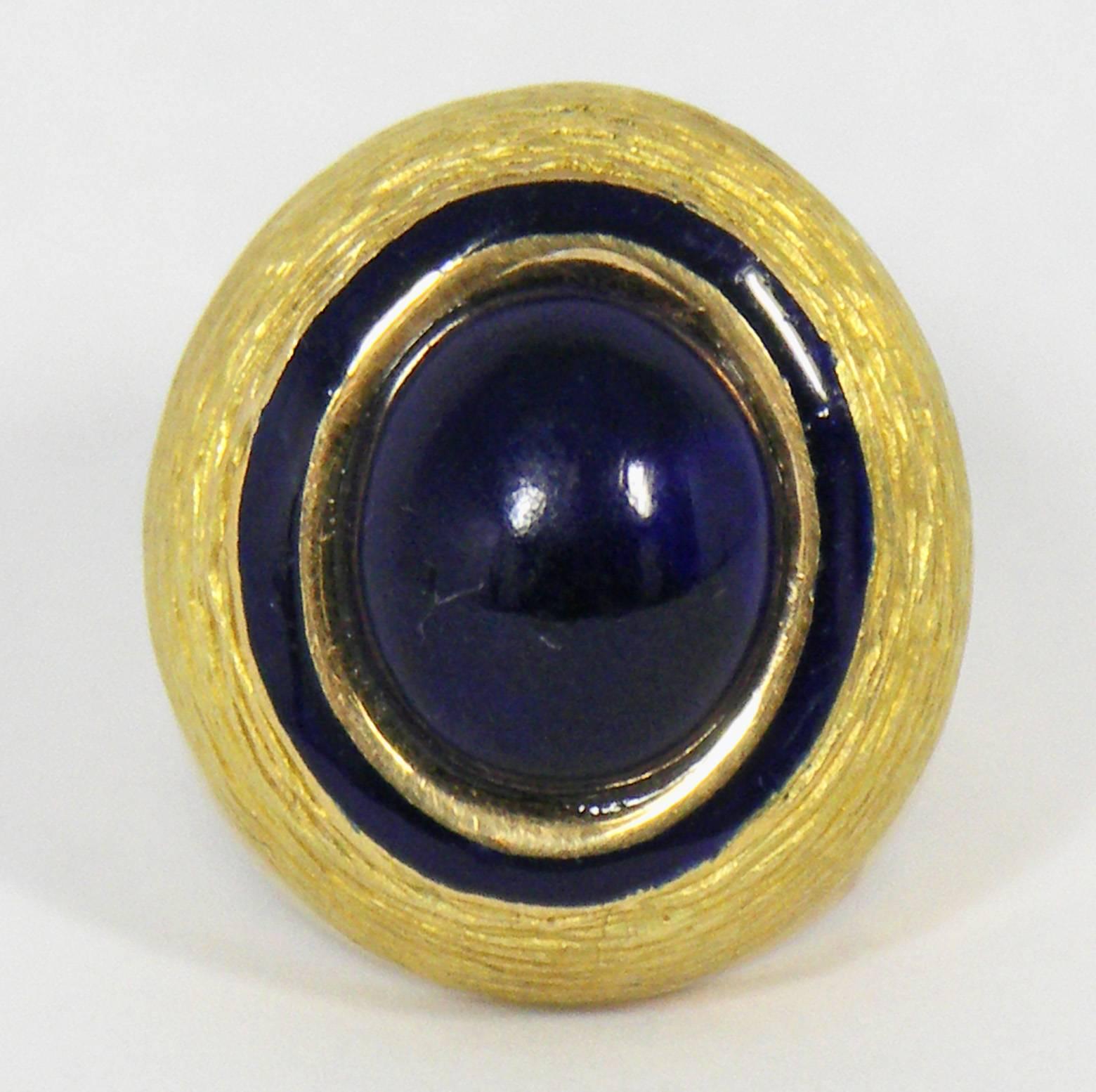 This stylish oval shaped 18k Yellow Gold ring is set with one oval
Lapis Lazuli cabochon measuring 15mm x 7mm. The navy blue enamel
line surrounds and highlights the center cabochon. The ring is currently
size 5, but can easily be resized. It weighs
