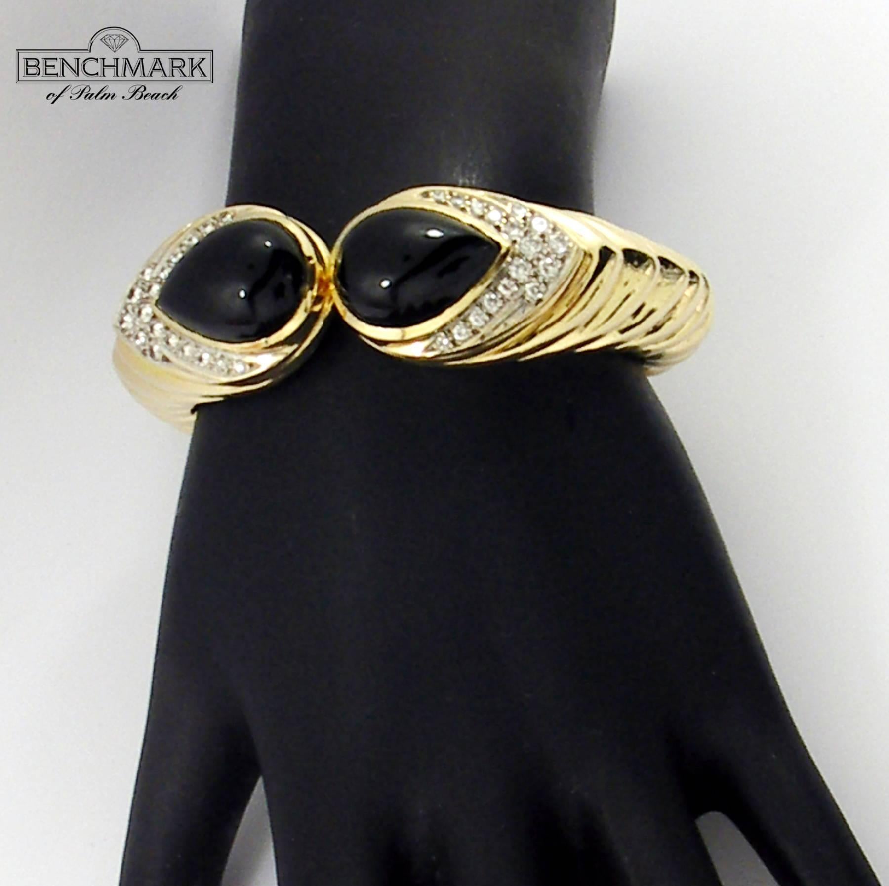 One 14K yellow gold clamper cuff bracelet featuring a tiered, split front design. On either side of the opening are Pear shaped onyx cabochons, accented by a total of 36 round brilliant cut diamonds. Diamonds weigh 1.35 ct total approximate weight