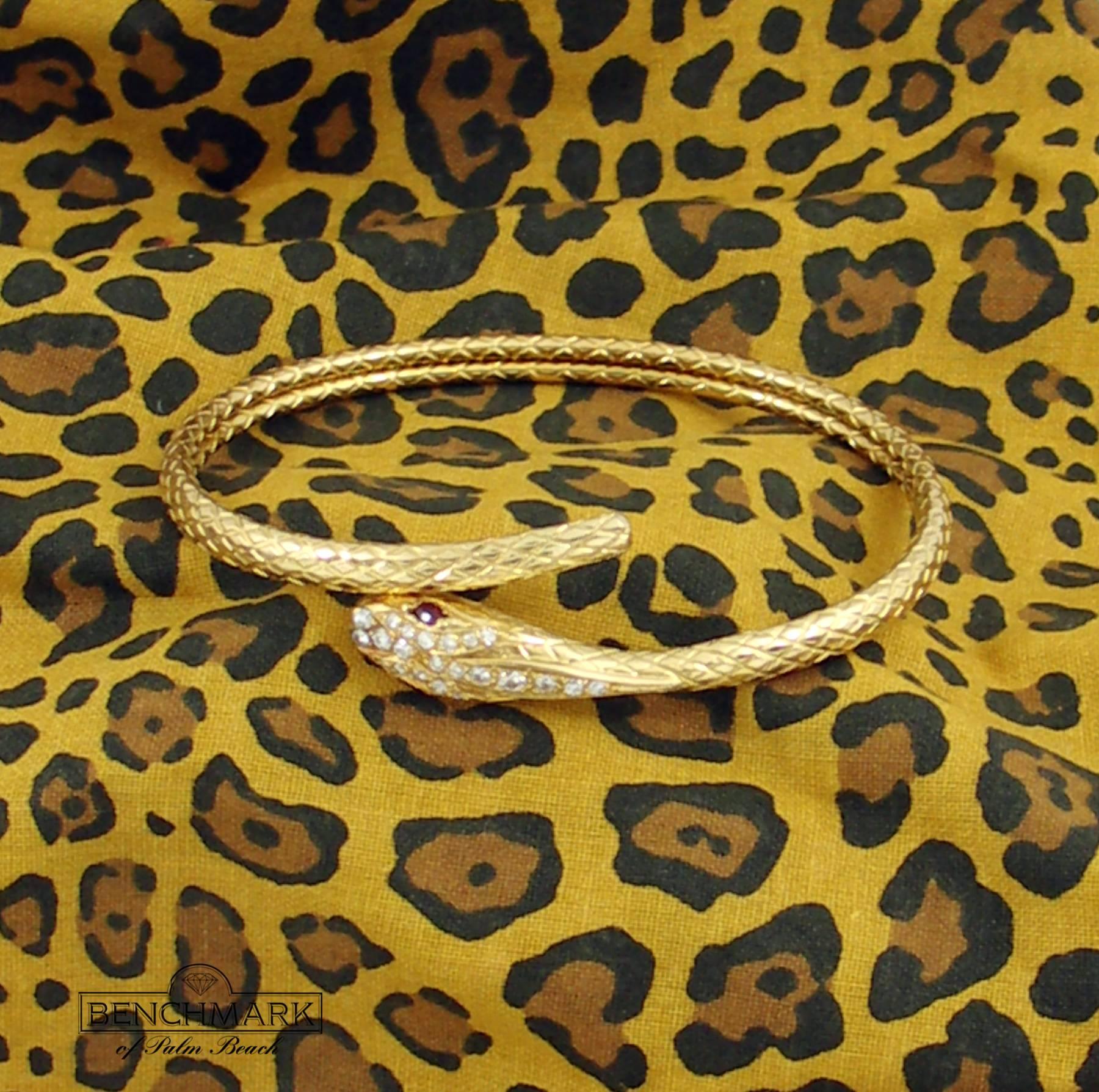 An 18K yellow gold, flexible, snake cuff, set with 23 round brilliant cut diamonds weighing 0.35ct total approximate weight, and 2 marquise cut rubies weighing a total of approximately 0.15ct. This sleek serpent measures 3/16 of an inch wide at the