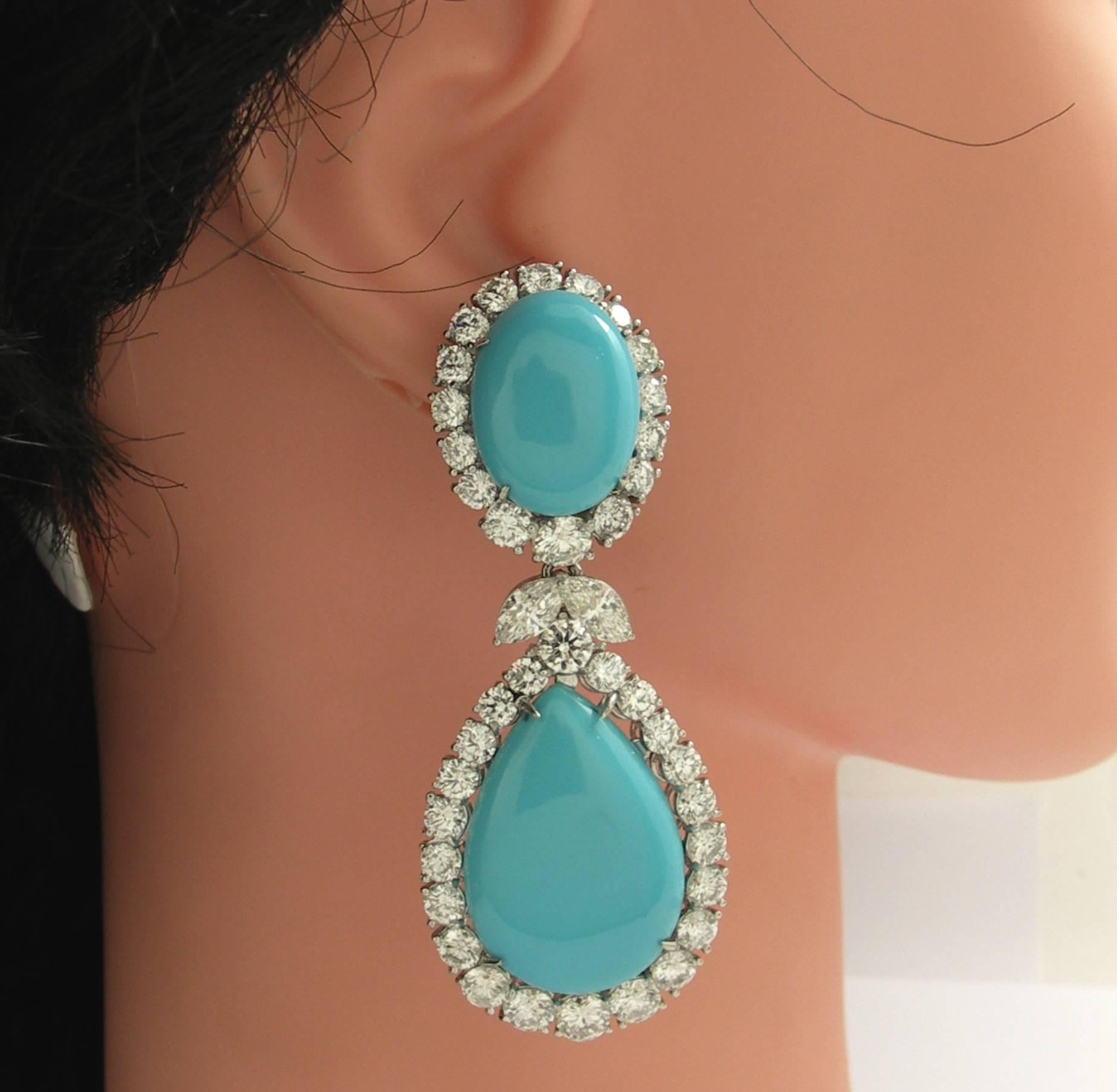 A pair of platinum hanging, doorknocker earrings, centered around oval and pear shaped cabochon turquoise, surrounded by diamonds. There are a total of 76 round brilliant cut diamonds weighing a total of approximately 15.66ct, and 4 marquise cut