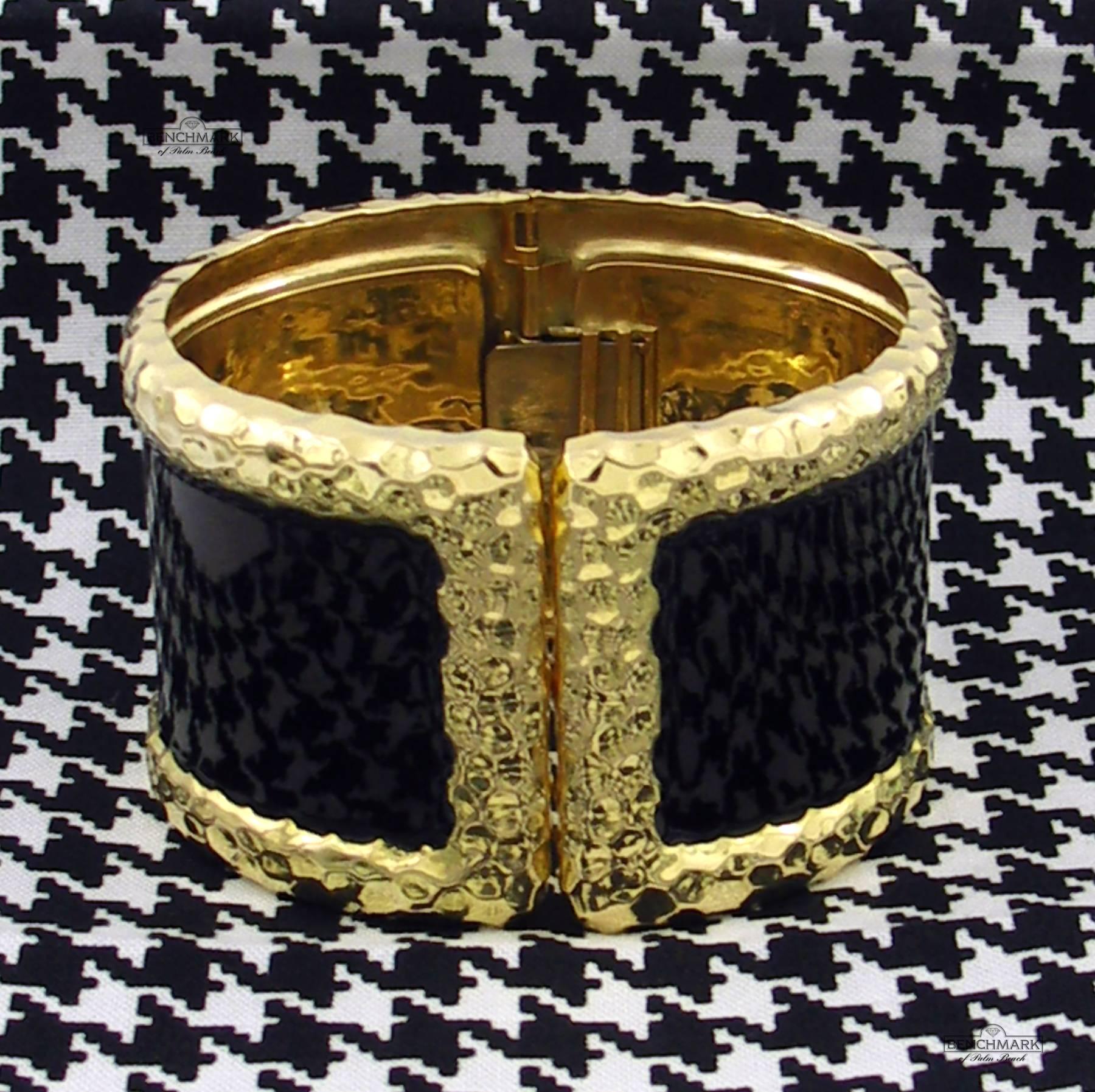 A robust 18K yellow gold bracelet measuring 1 3/4 inches wide, with deeply hammered edges, and a strip of black enamel measuring 1 1/4 inches wide. This hinged cuff opens at its split front, for a classic look.  Fits a small to medium size wrist,