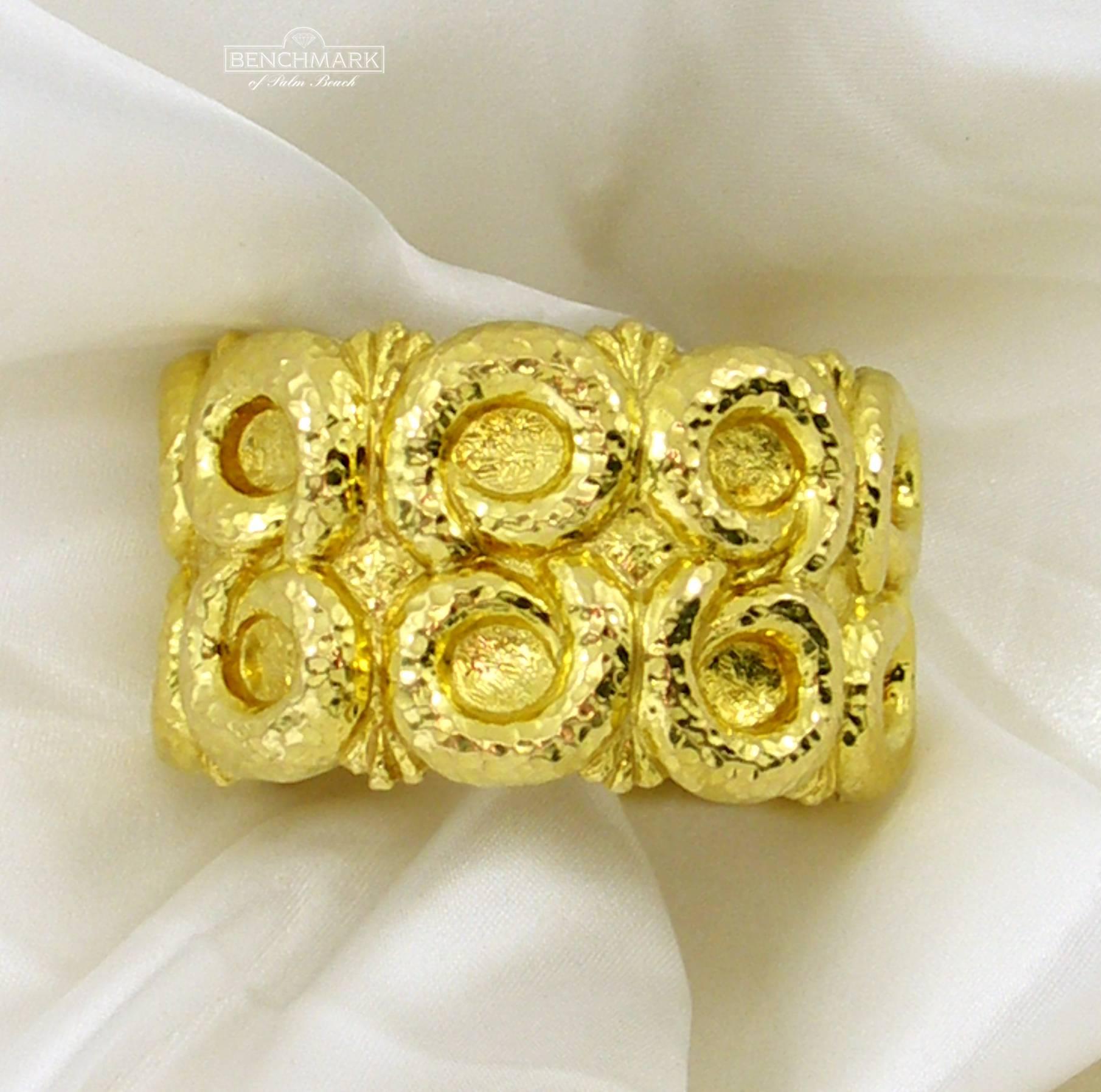 An 18 karat yellow gold bracelet measuring 1 1/2 inches wide, with two rows of Greek inspired design, it is hammer finished for a deep ancient look. In between the swirling shells are trident like motif, so that no design space is wasted. Signed