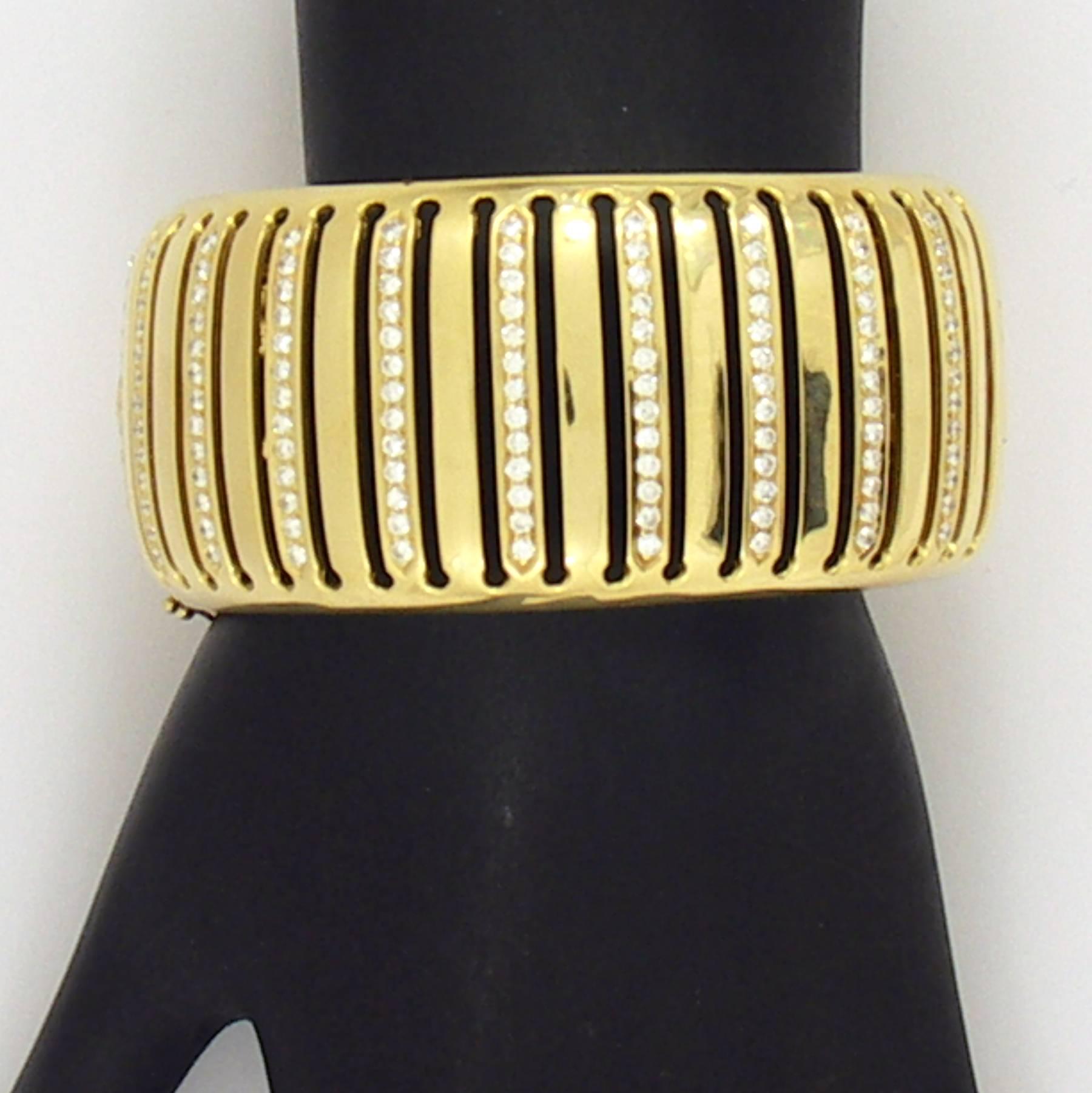 An 18K yellow gold, hinged cuff bracelet, measuring 1 1/8 inches wide, with a birdcage design. The top of the bracelet features alternating gold and pave' set diamond slats. There are 130 round brilliant cut diamonds for a total approximate weight