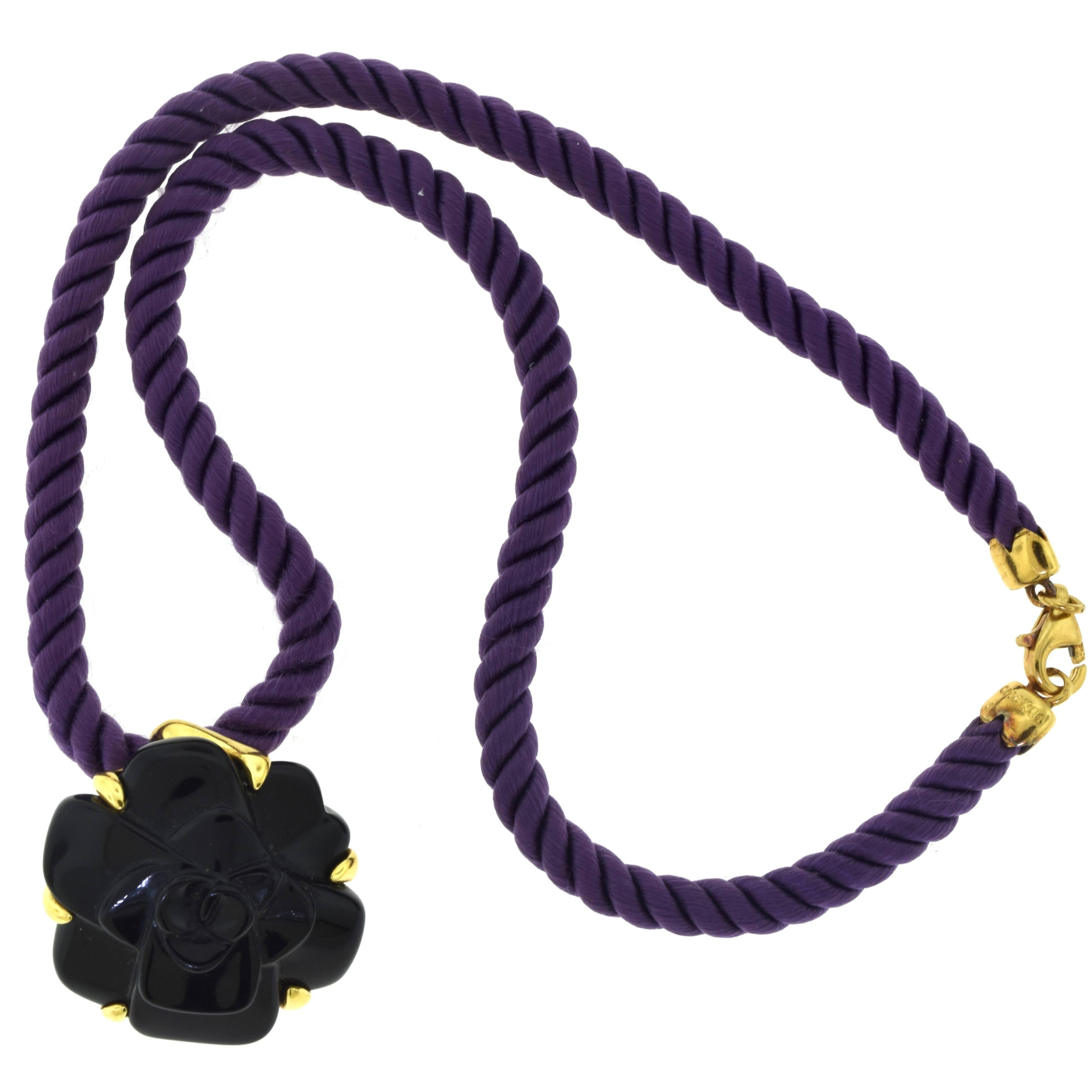 From Chanel's Camellia Collection:

Metal: 18 Karat Yellow Gold
Strap Material: Purple Silk Cordon Braid
Necklace Length: 16