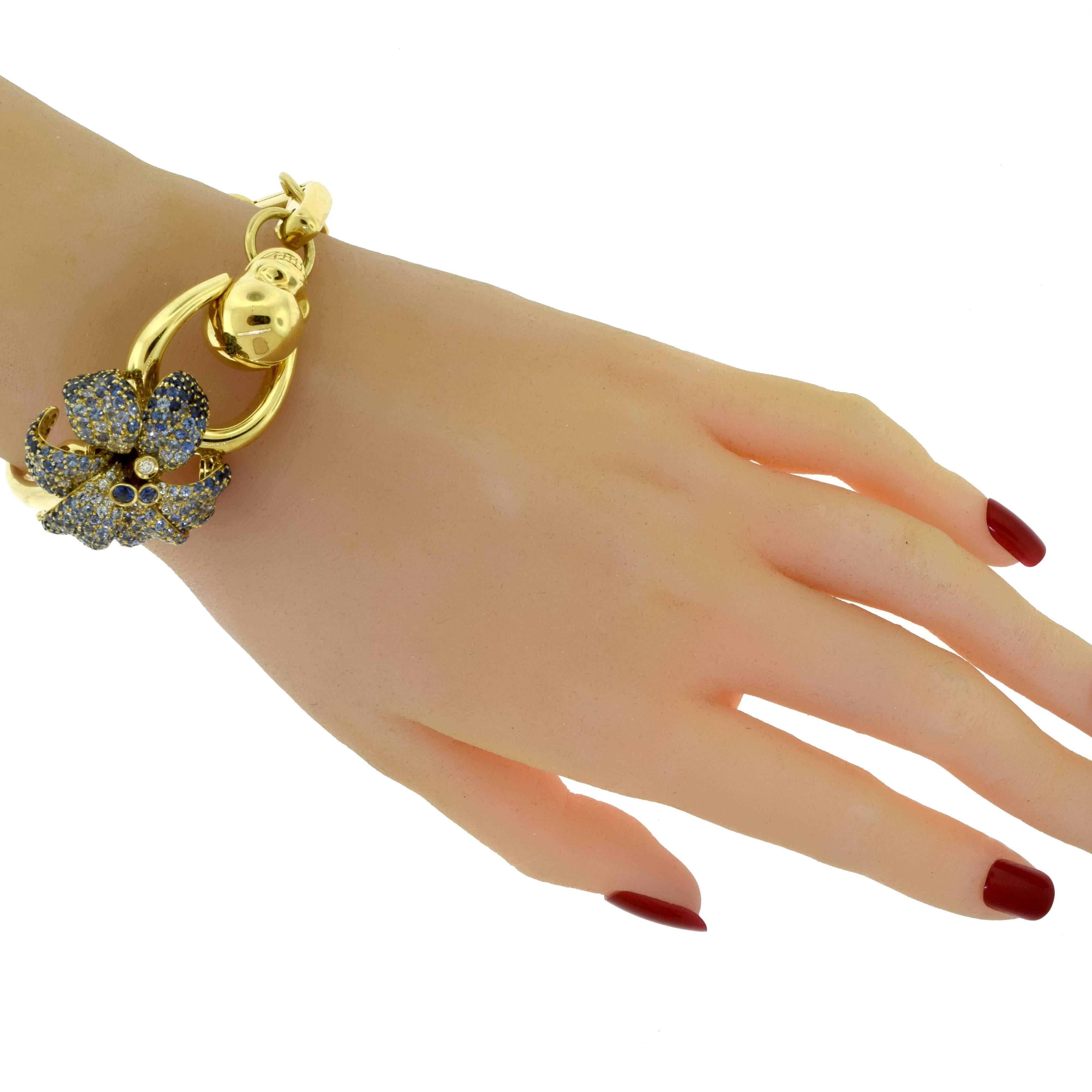 Designer: Gucci
Collection: Flora
Metal: 18 Karat Yellow Gold
Stones: Sapphires weighing 7.29 ct
Diamonds weighing 0.05 ct
Bracelet Size: 17 = 17 cm
Flora Dimensions: 1.00 x 1.25 inches
Skull Dimensions:  0.75 x 0.5 inchs
Total Item Weight (g):
