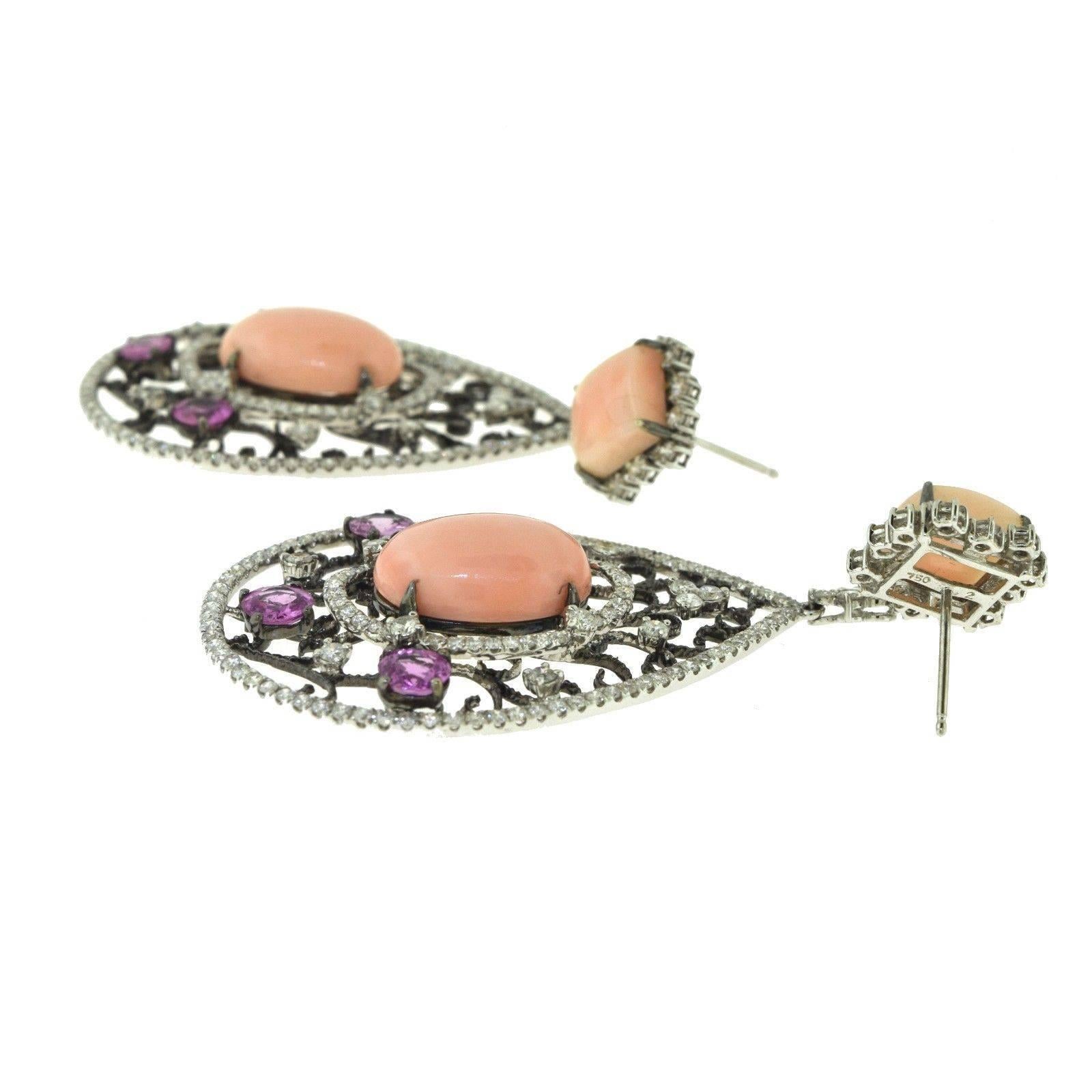 Gorgeous long dangle earrings in 18k white gold, composed of the most delegately intertwined filigree style adorned with three round sapphires for a total of 6. The natural pink coral stones add the most beautiful touch of elegance along with the