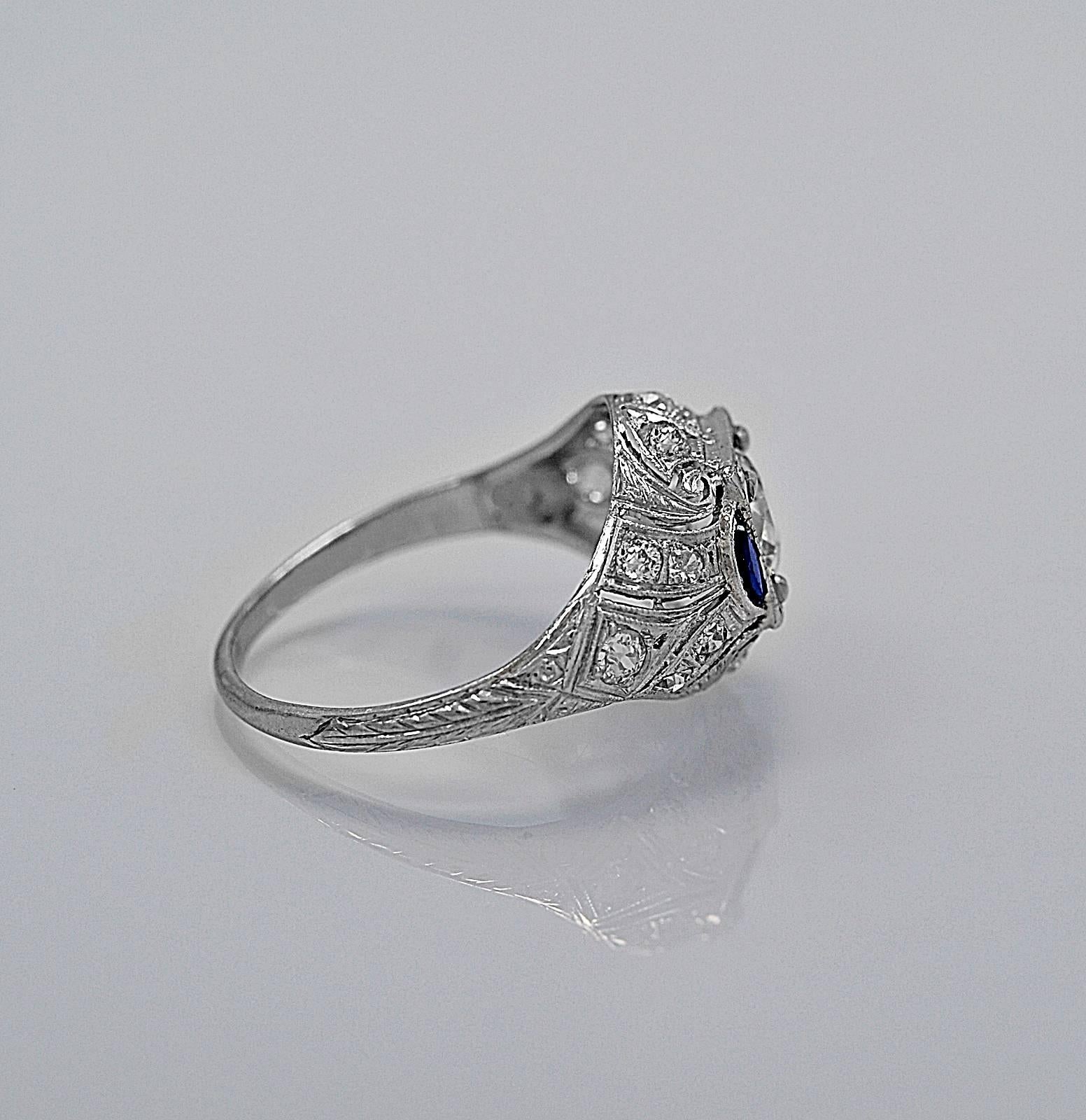 A blazingly beautiful vintage engagement ring featuring a .90ct. apx. European cut diamond with VS1 clarity and J-K color. The ring is accented with .25ct. apx. T.W. of synthetic sapphires (consistent with time period). This ring has amazing detail