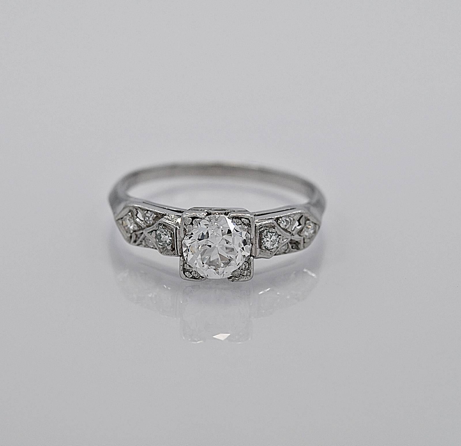 An antique engagement ring crafted in platinum and features a .94ct. apx. center diamond with SI1 clarity and G color. The side diamonds are .12ct. apx. T.W. and gently decorate the sides of the center diamond, east to west. The trefoil prongs on