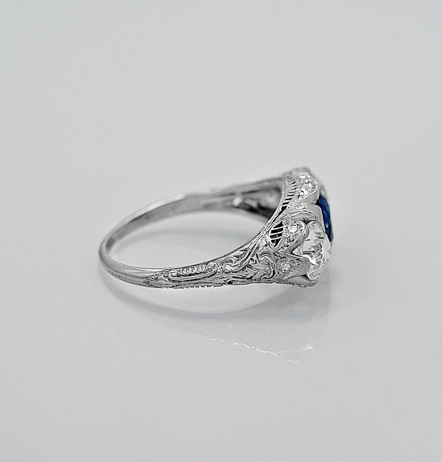 A wonderful antique 3 stone engagement ring from the Art Deco period that features a 1.25ct. apx. rich blue natural sapphire. It also showcases two European cut diamonds with 1 weighing .80ct. apx. and the other weighing .85ct. apx. with VS1-VS2