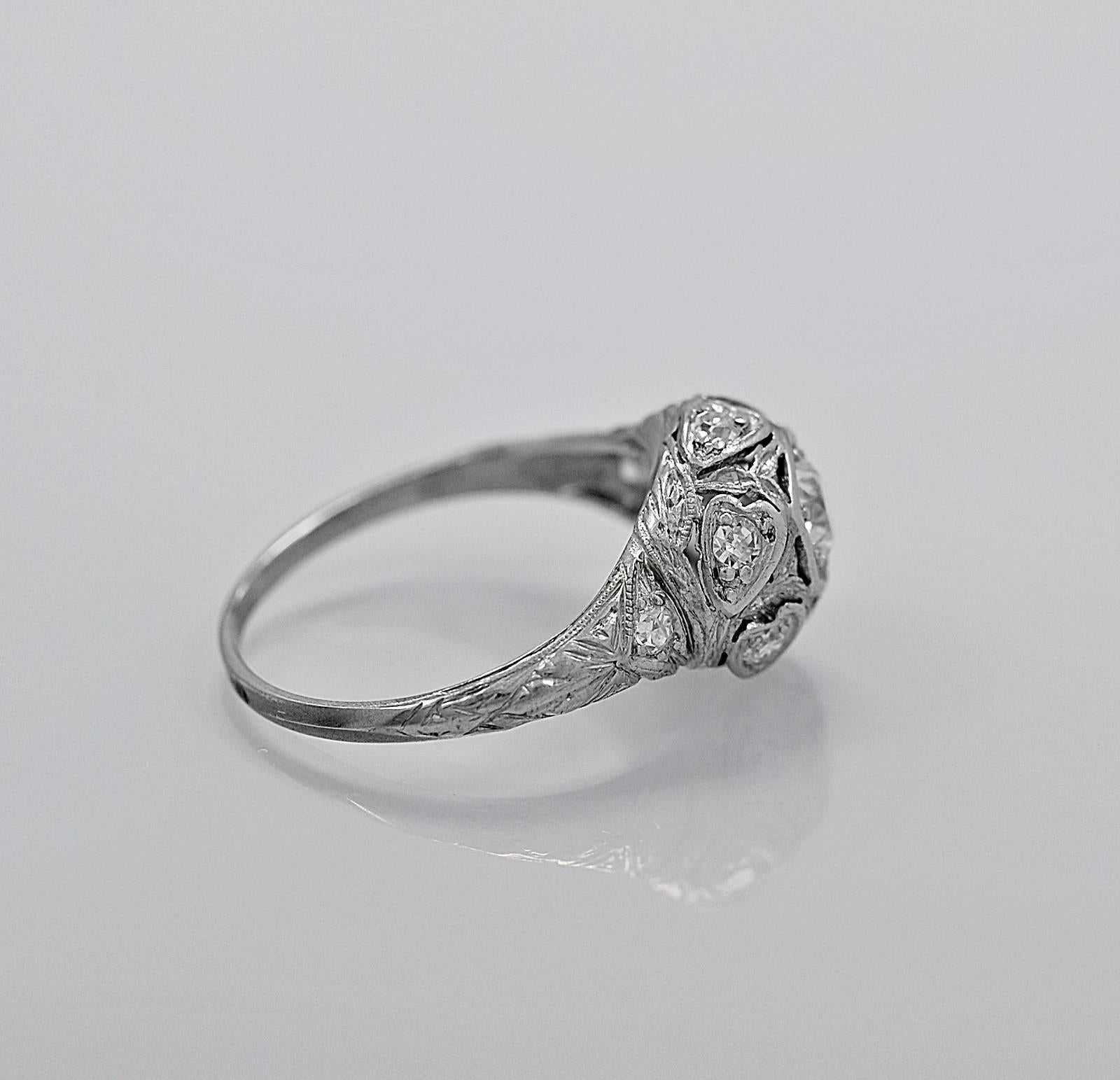 A decorative antique engagement ring featuring a .33ct. apx. European cut diamond with VS1 clarity and K color. The uniquely designed mounting has .16ct. apx. T.W. of accenting diamonds that are surrounded with heart shaped bezels. The shank is