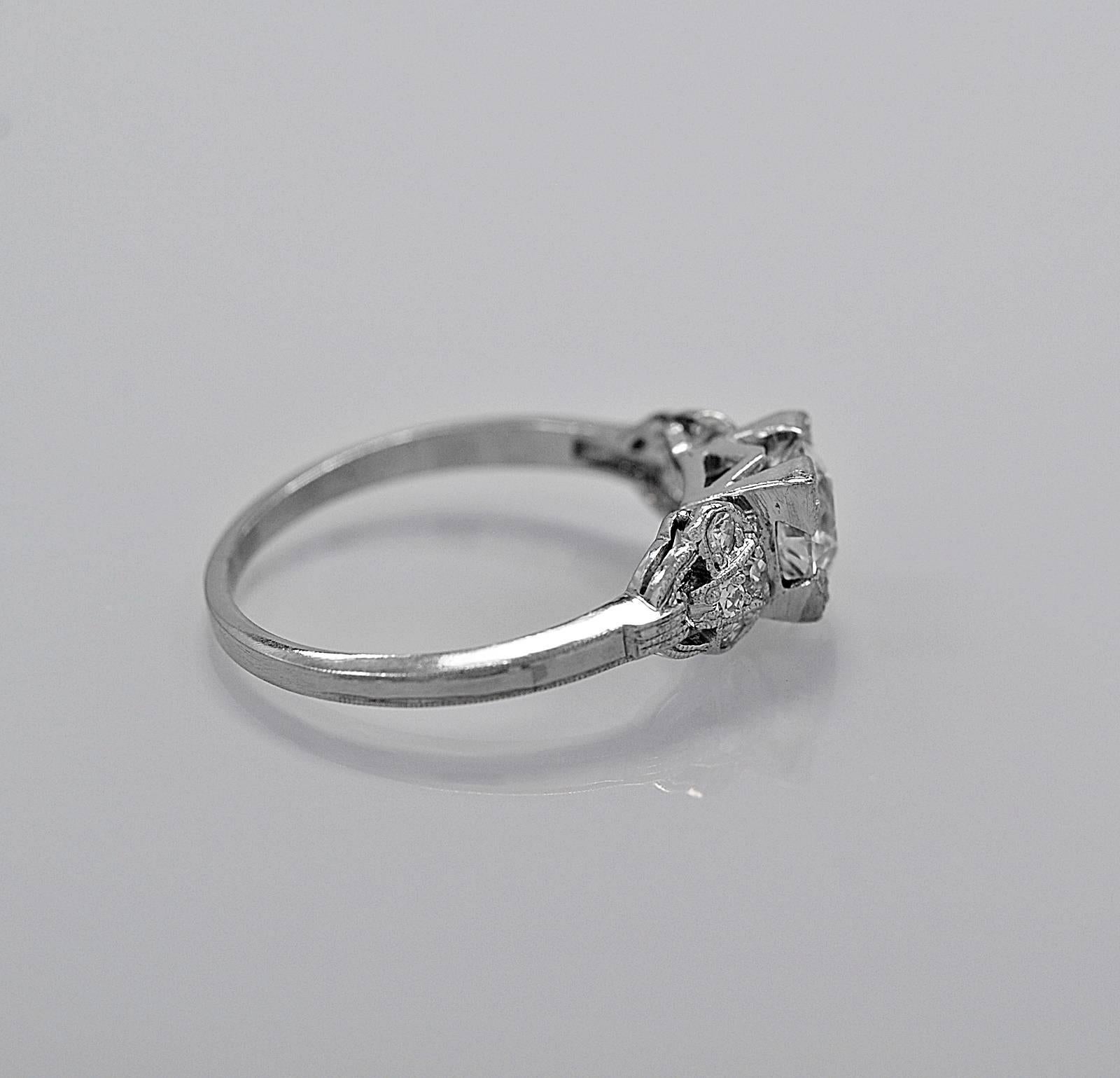This antique engagement ring is crafted in platinum and features a .70ct. European cut diamond with VS2 clarity and I color. The center diamond has trefoil prongs giving it a squared off look. The accompanying diamond melee decorate the sides of