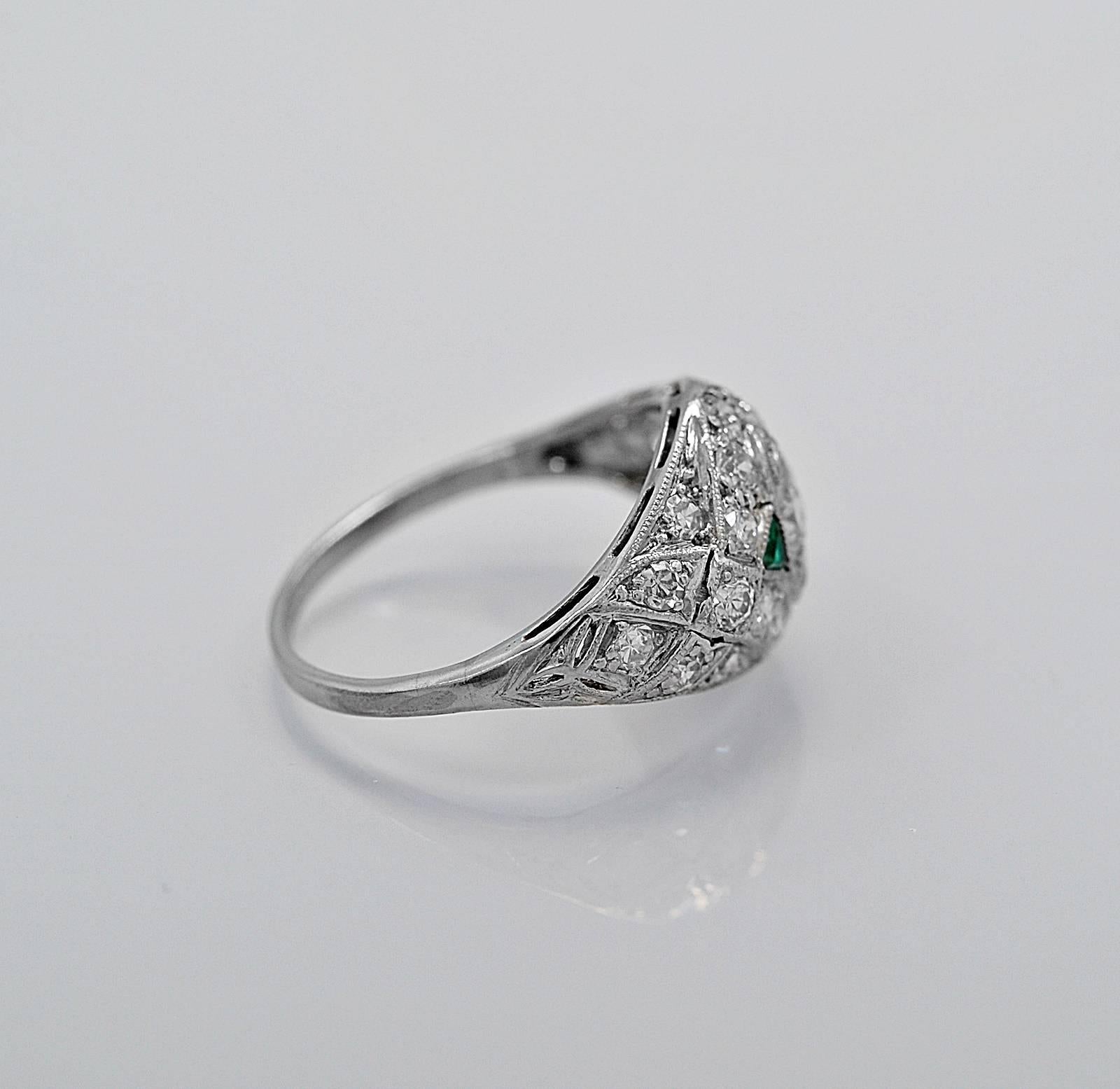 A stunning antique engagement ring or fashion ring featuring a center diamond that is .20ct. apx. with VS2 clarity and H color. The center diamond is accented with two triangular shaped natural emeralds. To balance off this fabulous one of a kind