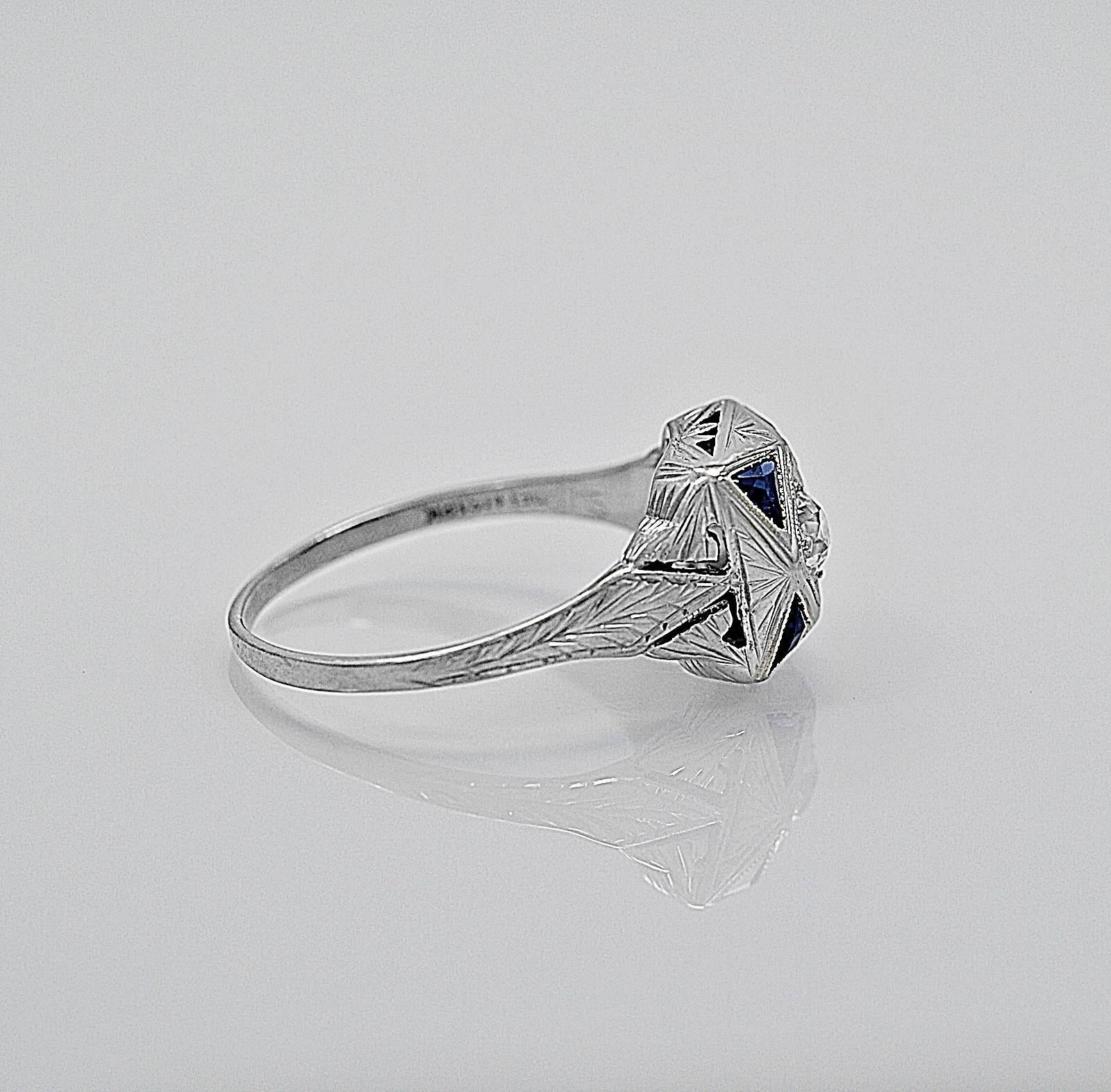 An artistically crafted 18K white gold antique engagement/fashion ring featuring a scintillating .20ct. apx. European cut diamond with exceptional VS1 clarity and equally exceptional F color. The center diamond is accented with four triangular