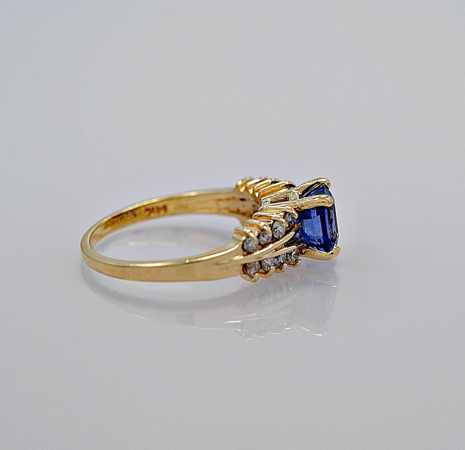 A sapphire engagement ring 1.50ct. natural sapphire in a square step cut style with accenting diamond melee weighing .20ct. apx. T.W. The ring is crafted in 14K yellow gold and this sapphire and diamond ring would be a wonderful alternative to the