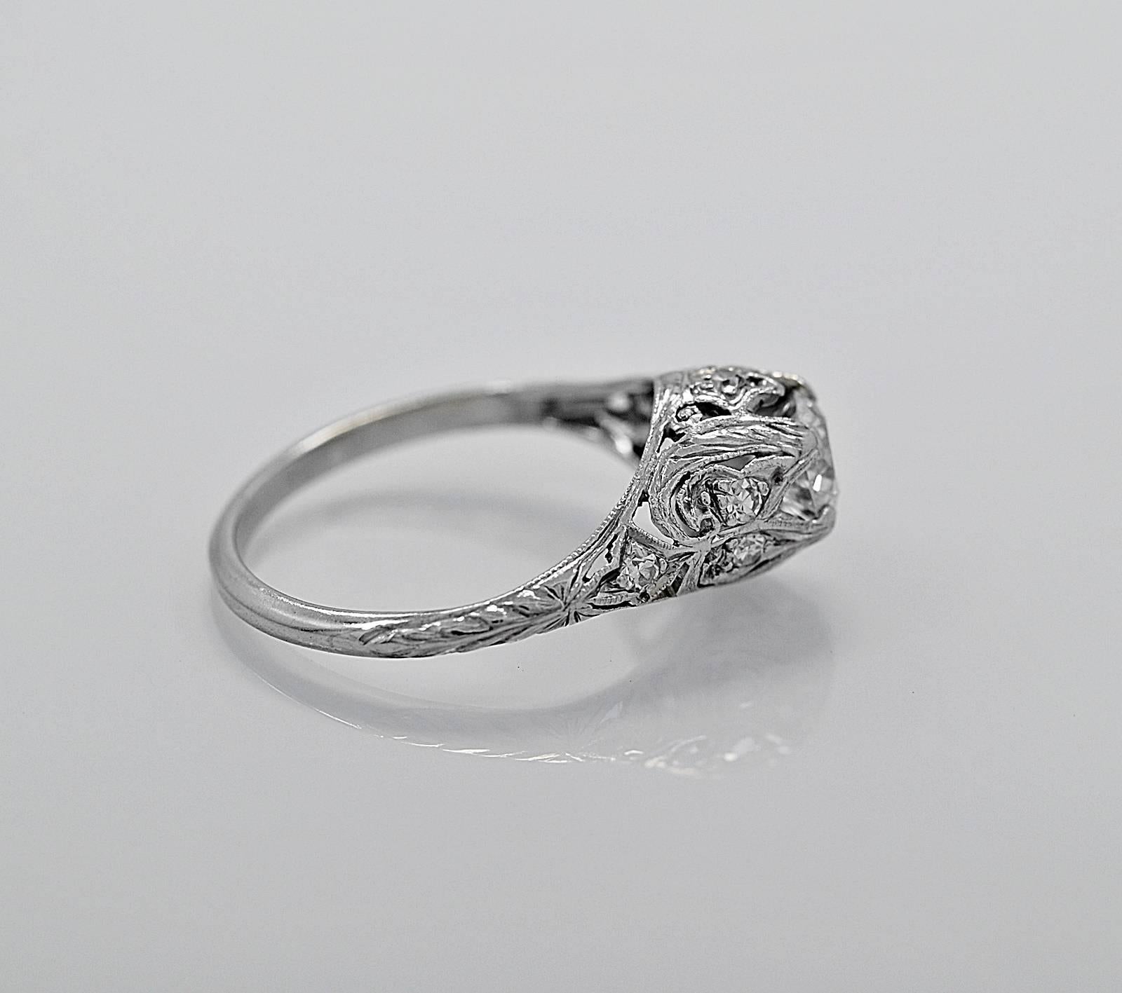 An exceptional Platinum & Diamond Art Deco antique engagement ring. This beautiful ring is highlighted by gorgeous filigree & pierced decoration, supporting a .63ct. apx. European cut diamond that is VS2 in clarity and G in color. The center diamond