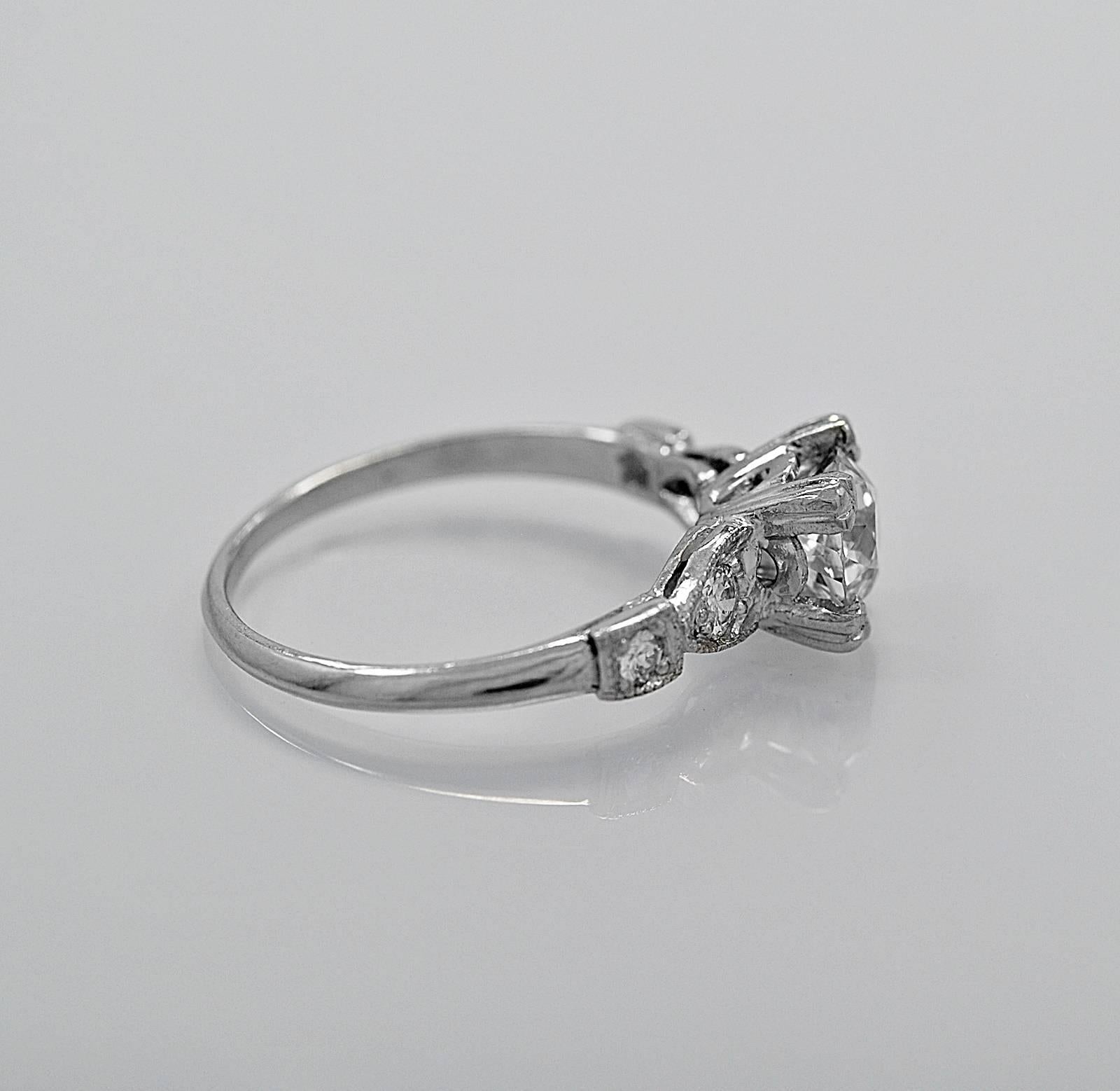 A dazzling Art Deco platinum diamond antique engagement ring featuring 1.00ct. apx. European cut diamond with I1 clarity (100% Eye Clean) and G color. The center diamond is set with trefoil prongs and the diamonds on the side are set in a heart