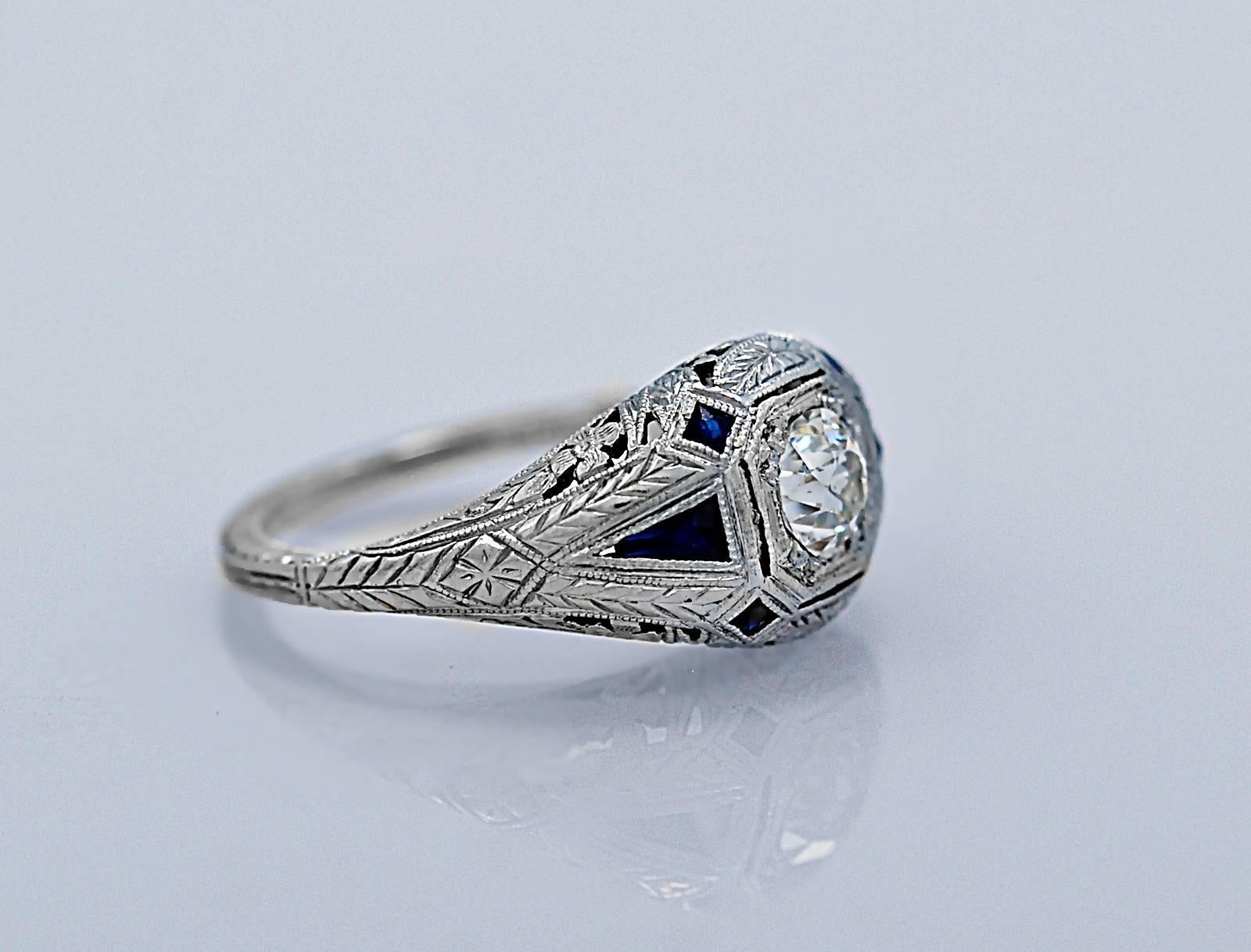 A highly distinctive Art Deco engagement ring featuring a .50ct. apx. European cut diamond with VS2 clarity and H-I color. In addition, there are .40ct. apx. T.W. of blue synthetic sapphires in triangular and square cut baguette shapes. Furthermore,