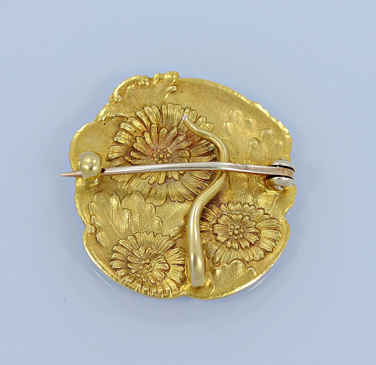 A meticulously hand crafted vintage Art Nouveau 14K Yellow Gold brooch featuring the profile of a lady with flowers in her hair and surrounding flowers and leaves. This craftsmanship carries to the reverse side where you will find more flowers and