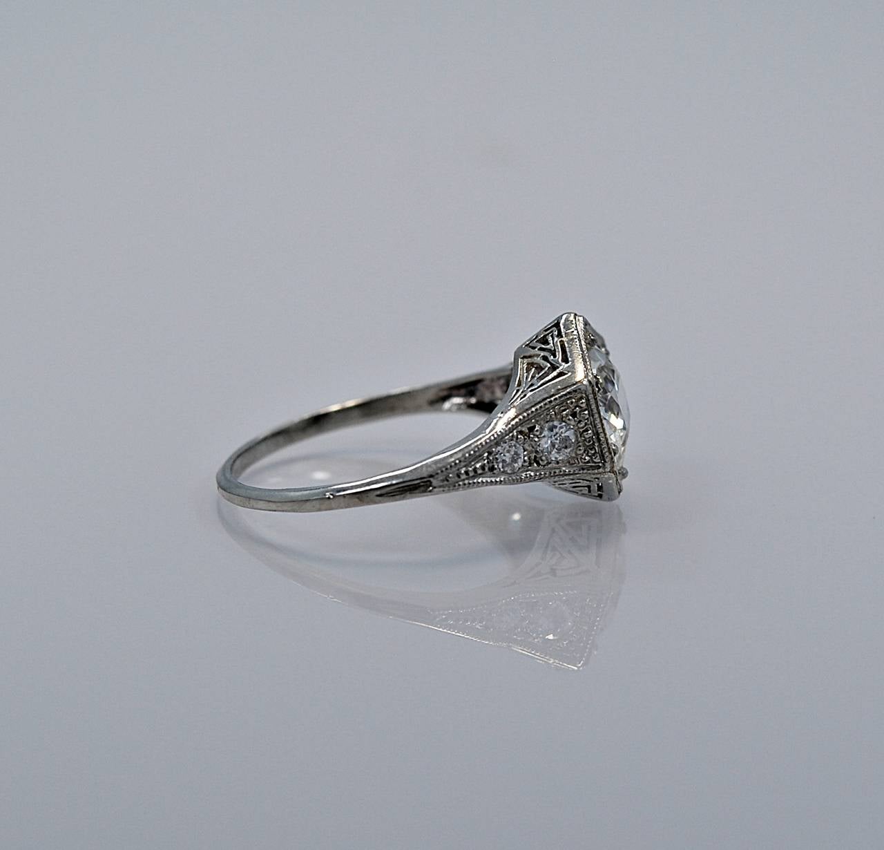 J34592

This Art Deco platinum engagement ring featuring a 1.23ct. apx. round European cut diamond with J color and VS1 clarity. The hexagon shaped head was popular during this time period. The gallery contains amazing geometric design and