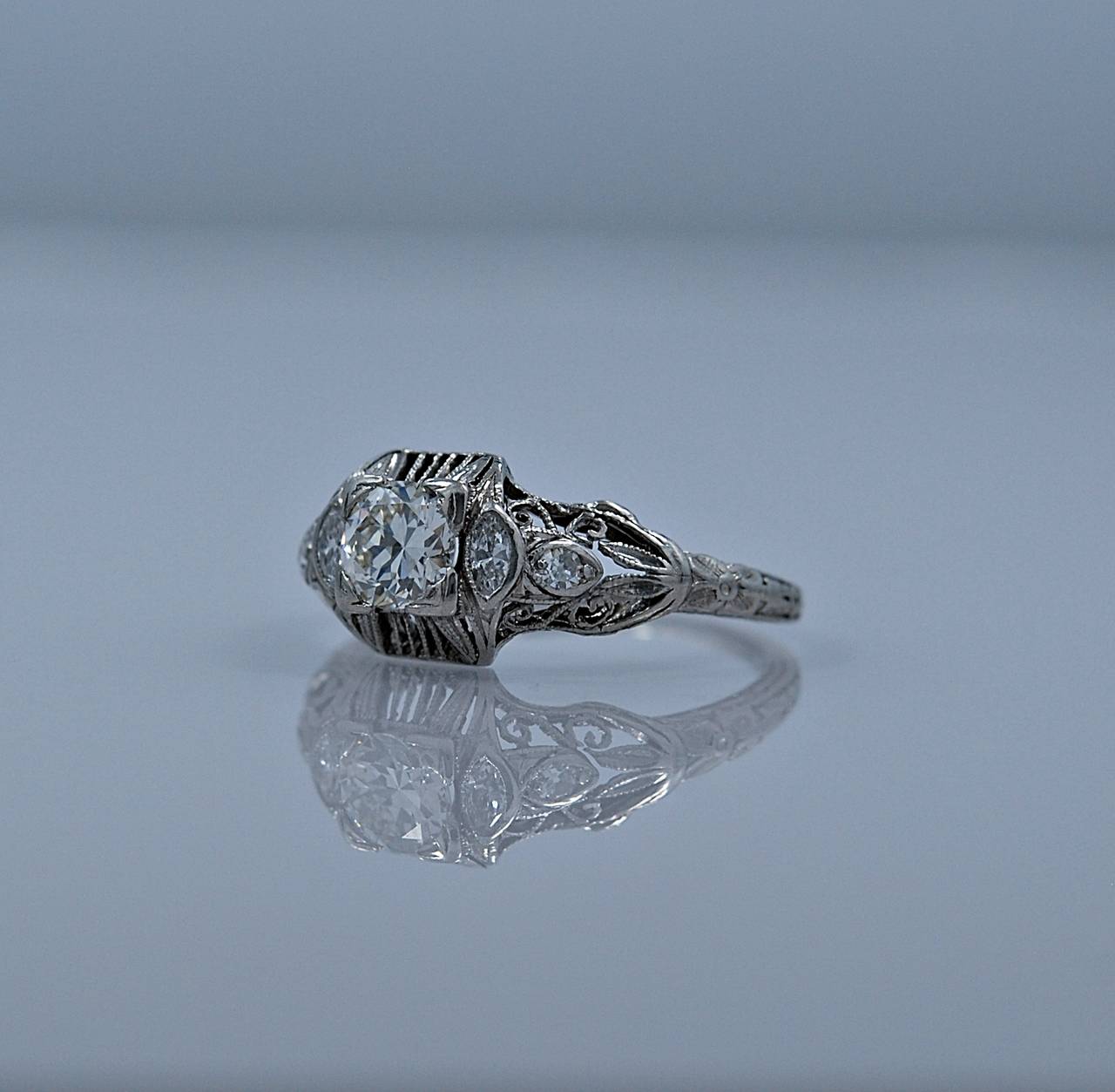 A meticulously filigreed Art Deco/Art Nouveau diamond engagement ring featuring a center diamond weighing .50ct. apx. with VS1 clarity and H color. The center diamond is accompanied with .25ct. apx. T.W. of diamond melee, specifically antique