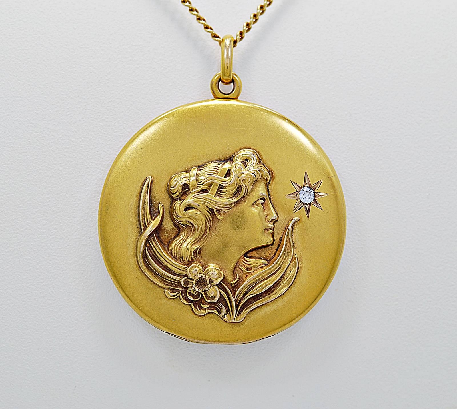 An Art Nouveau locket featuring an Art Nouveau ladies profile with leaves, a flower and a .08ct. diamond with I1 clarity (100% eye clean) and H color. This magnificent piece of artwork is created in rich 14K yellow gold with a 21