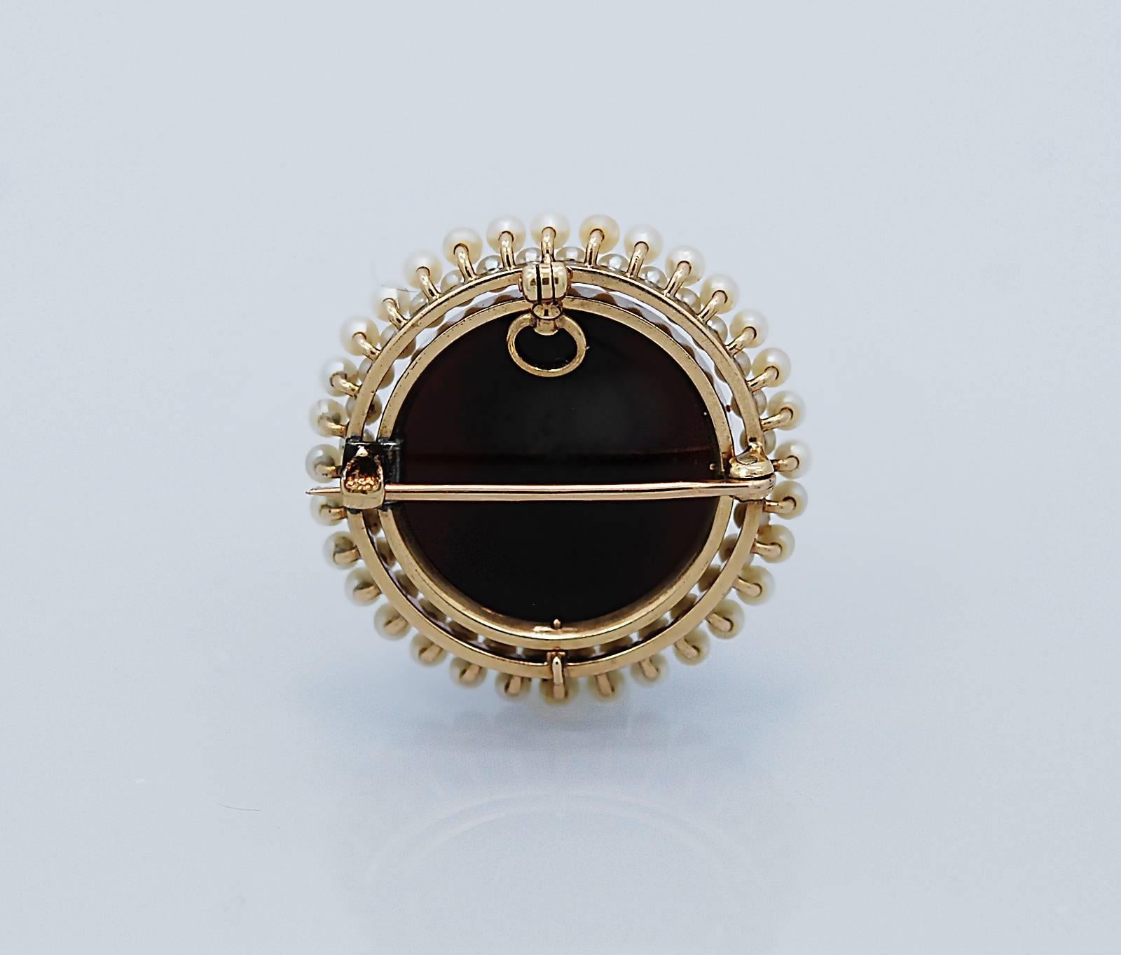 A gorgeous Sardonyx Antique hardstone cameo pin/pendant with a detailed woman's bust created and signed by master carver, Marguerite, and numbered 5. This cameo is surrounded with two circles of seed pearls and is crafted in 14k yellow gold.