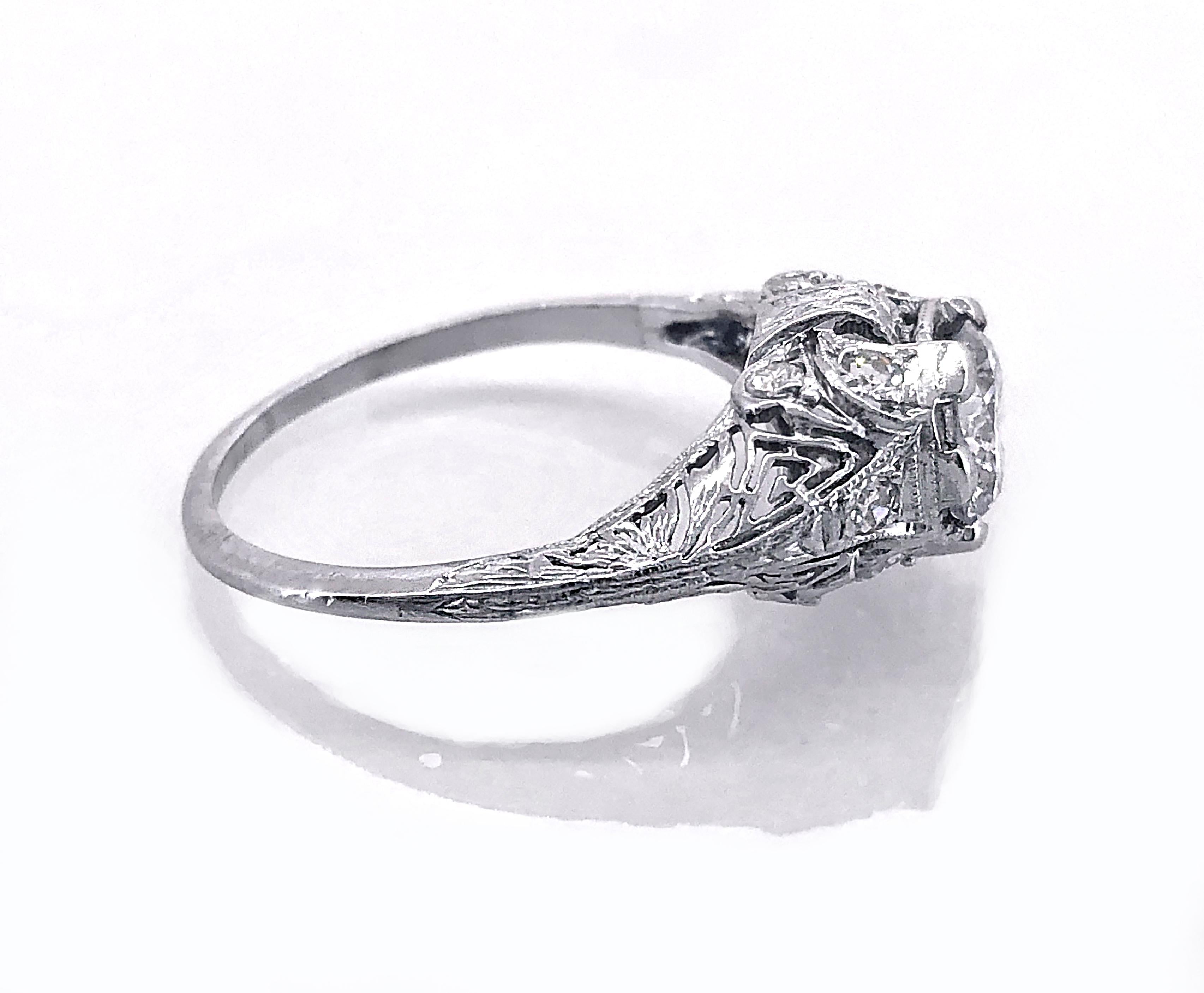 An Edwardian platinum and diamond Antique engagement ring featuring a .94ct. apx. diamond center of SI2 clarity and J color. This ring exhibits intricate filigree and .20ct. apx. T.W. of accenting diamonds. The complimenting diamond and meticulous