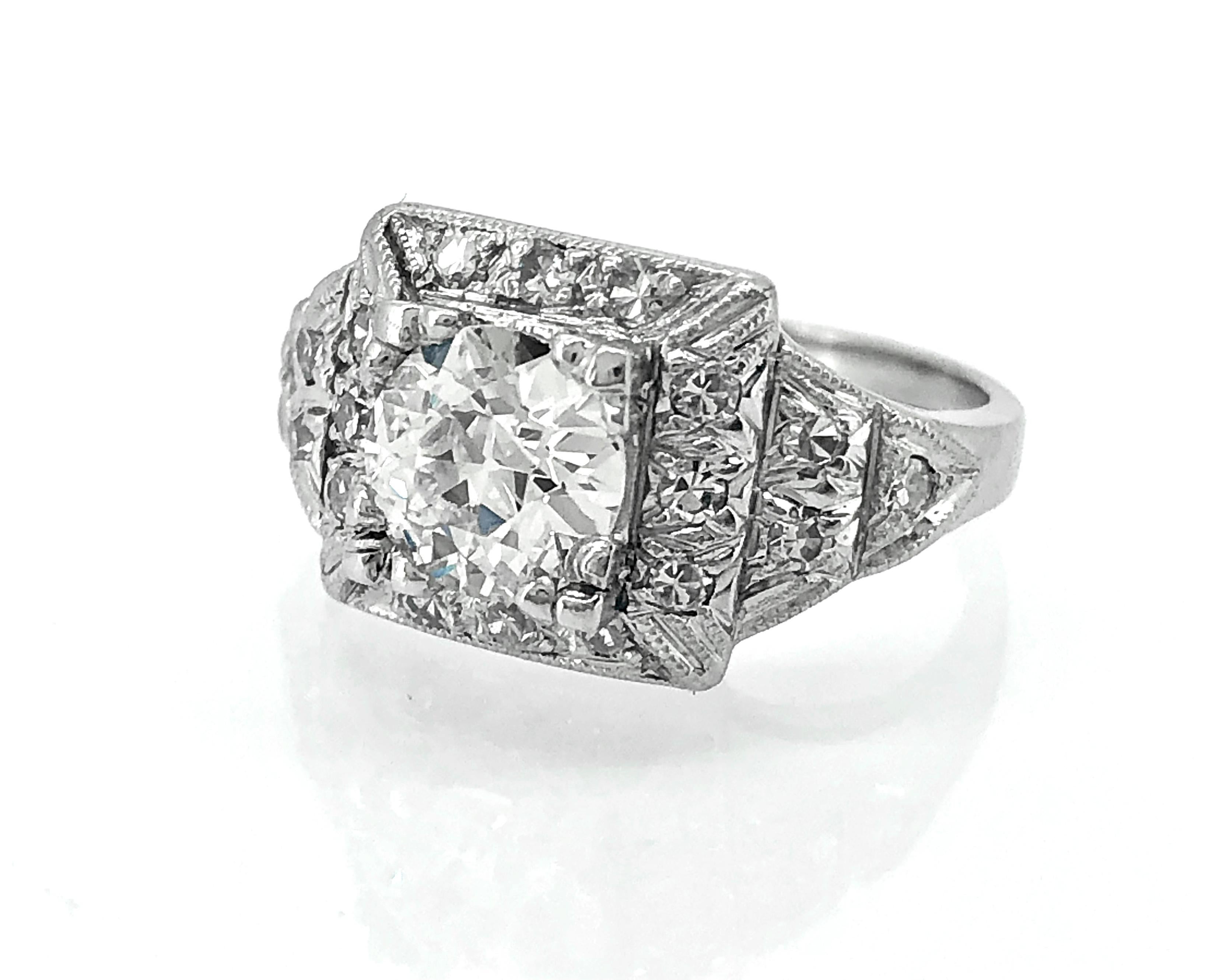 An exceptionally beautiful Art Deco engagement ring featuring a center diamond weighing 1.23ct. apx. of I color and VS2 clarity. The shoulders have 3 step down panels featuring bright and lively diamond melee. The square top is framed by smaller