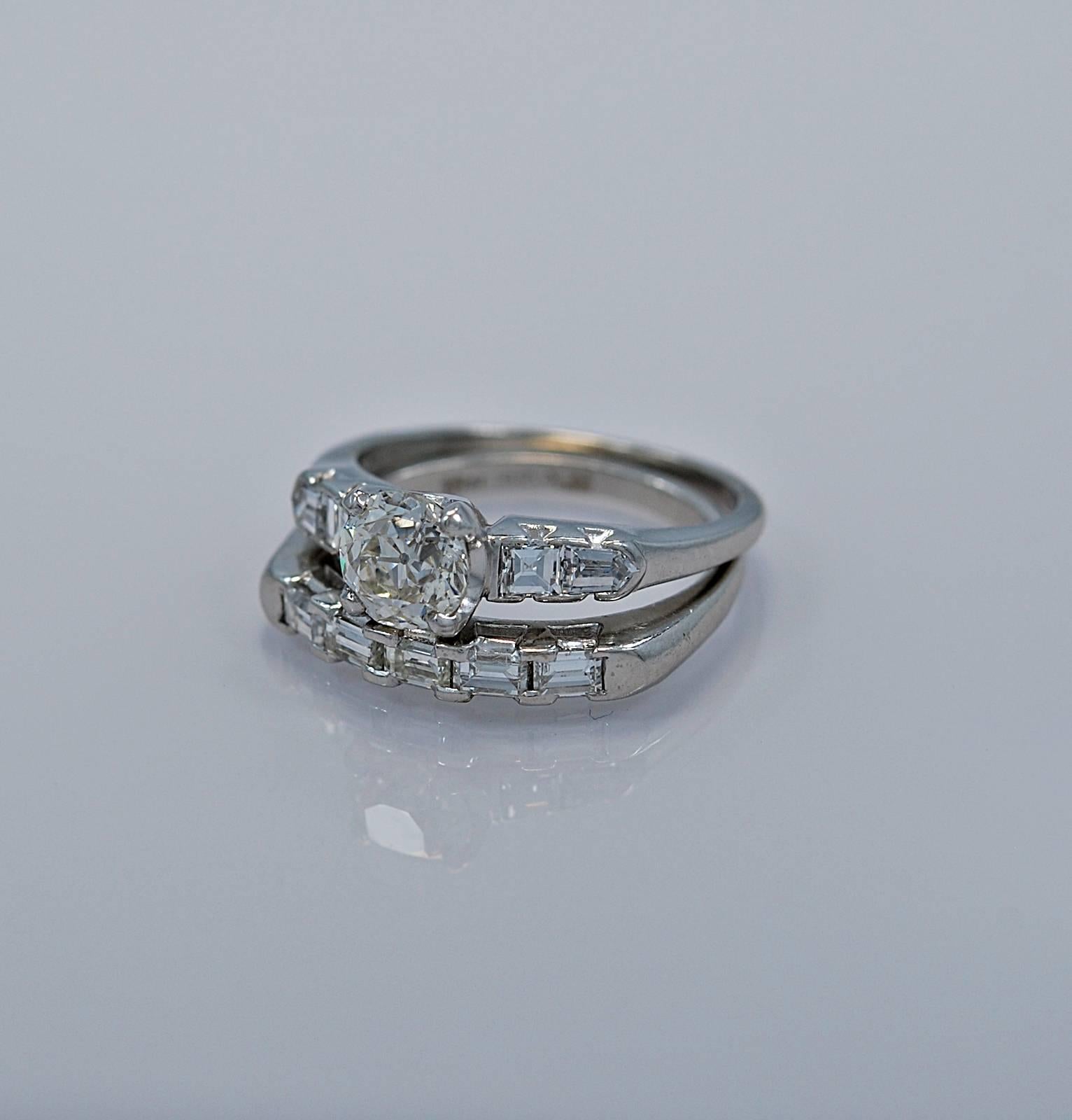 An Art Deco platinum diamond wedding ring set featuring a .90ct. apx. European diamond and accenting .50ct. apx. T.W. of bullet and emerald cut diamonds on both the engagement ring and wedding band. Geometric in design and artfully finished giving