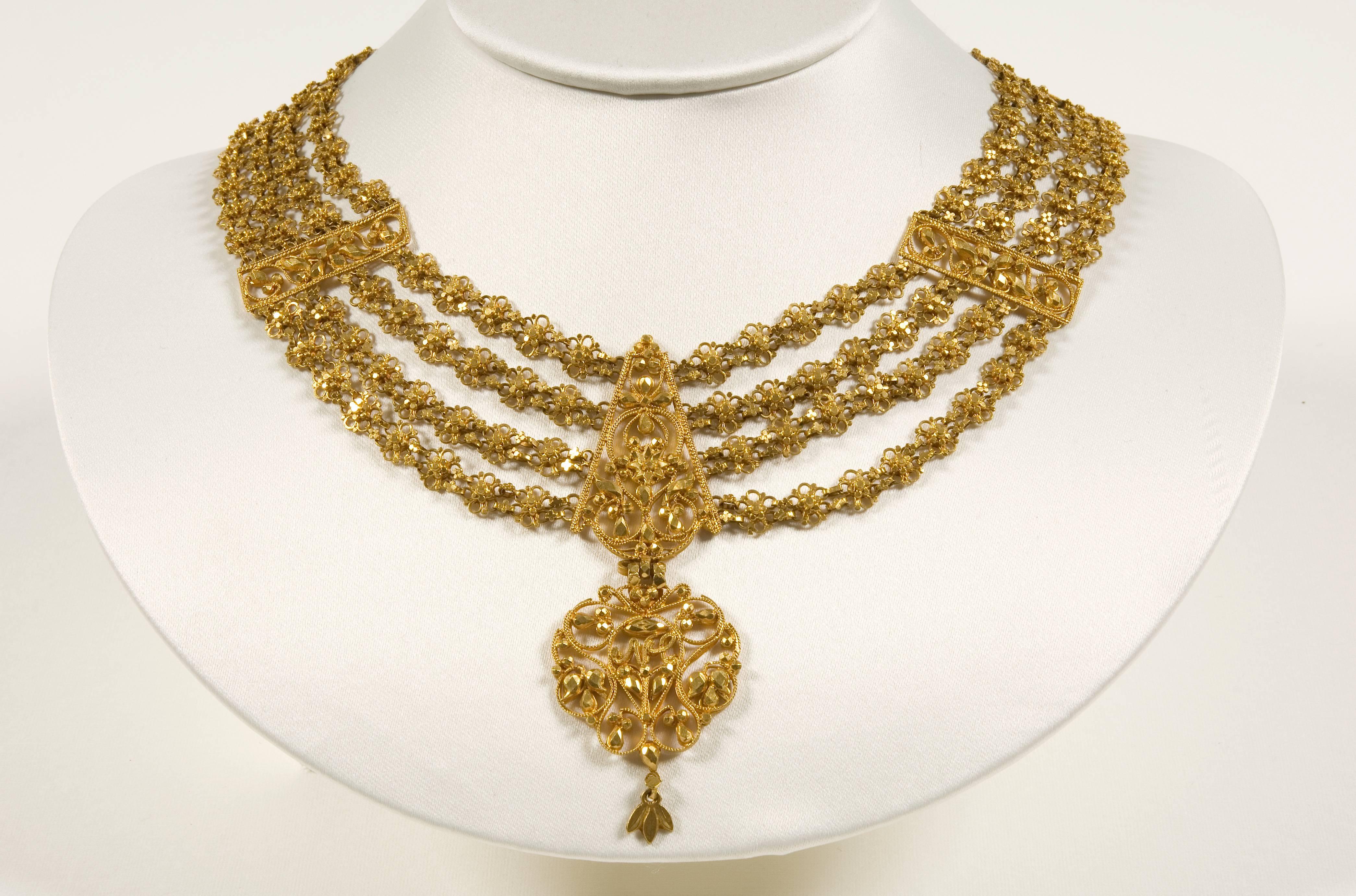 A 22ct gold necklace of pierced, chased and cut gold linked florets with applied granulation and minute flat discs, and with a suspended floral pendant.

India, West Bengal, Calcutta, 19th century
