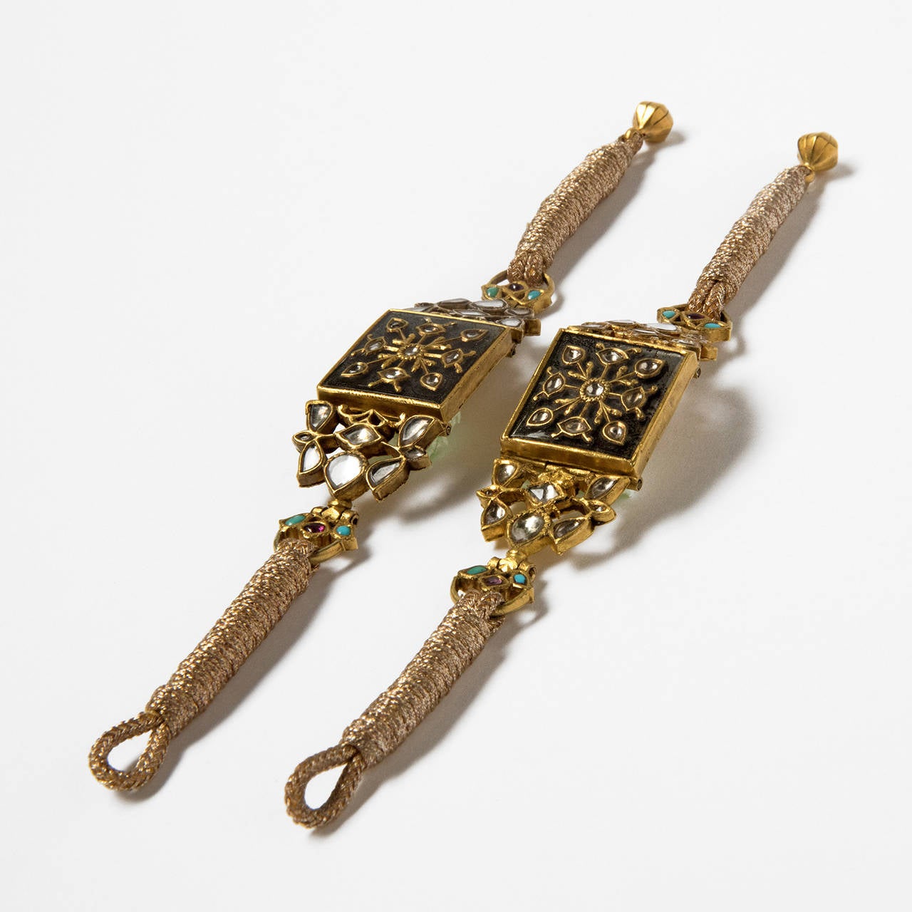 A pair of gold BAJU BAND,  the rectangular centre piece a square plaque, kundan set with rock crystal in gold collets on a base of foiled rock crystal, in gold frame, flanked by openworked trefoils, attached at an angle facilitating comfort to the