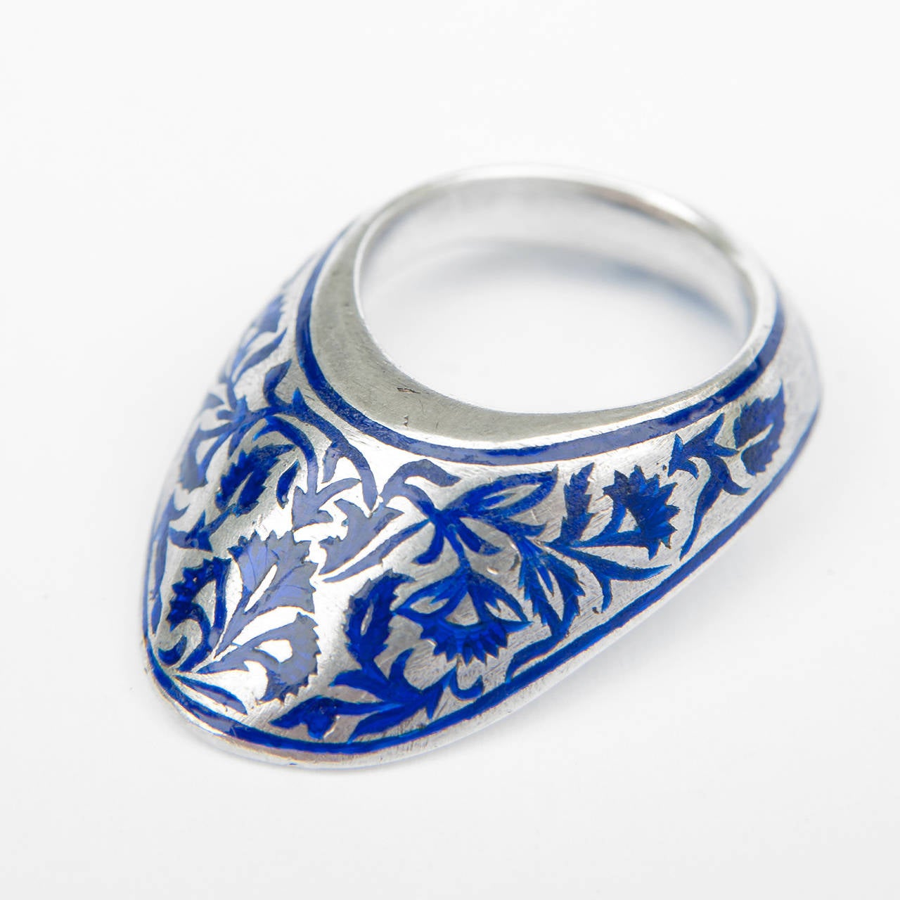 A silver archer’s ring decorated in champlevé technique with gardan – e - talus (peacock blue) enamel in a foliage and floral design to the front, the concave reverse with a similar enamel but different decoration of an open flower with garlands.