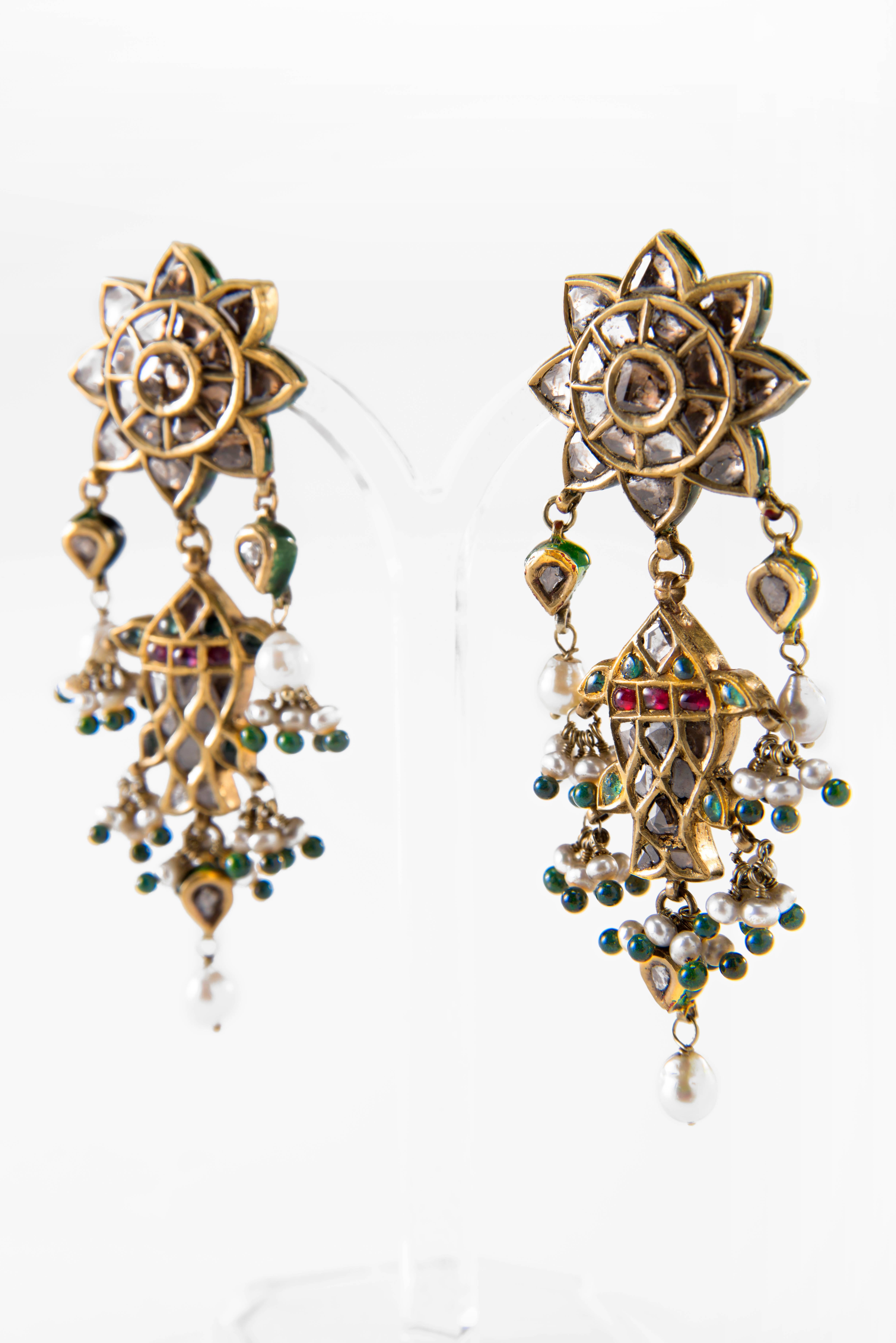 A pair of 20ct gold double ear pendants, jhale, set with colored stones on red and green foil and flat cut diamonds. The top is a flower shape rosette and suspended a fish, machhli, with stones set on both sides. The reverse of the flower top is