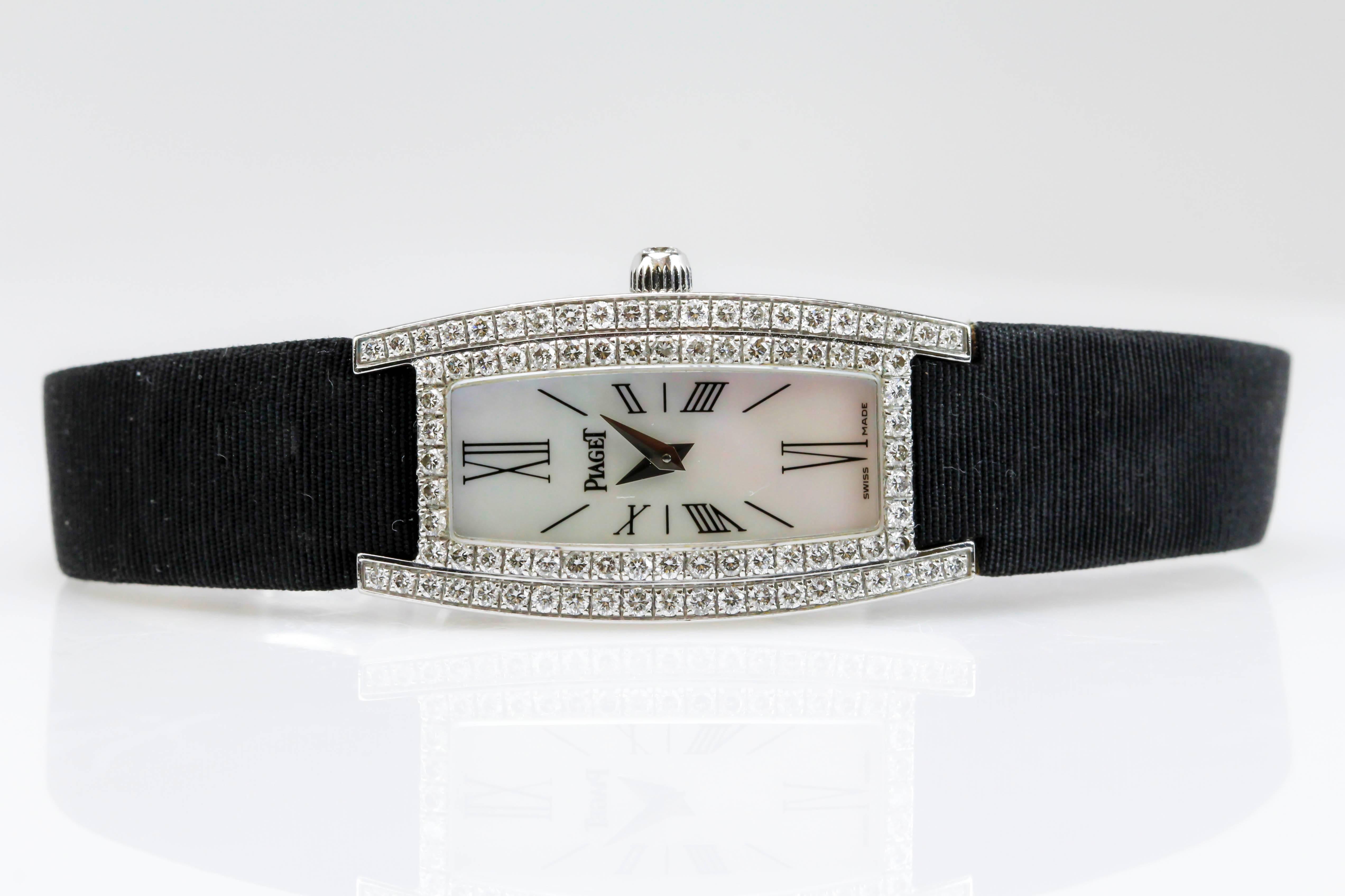 This is an elegant,Piaget Limelight reference 54035 with a tonneau-shaped, curved, 18K white gold, mother of pearl, diamond lady's quartz wristwatch with a silk black strap and white gold/diamond deployant clasp. 